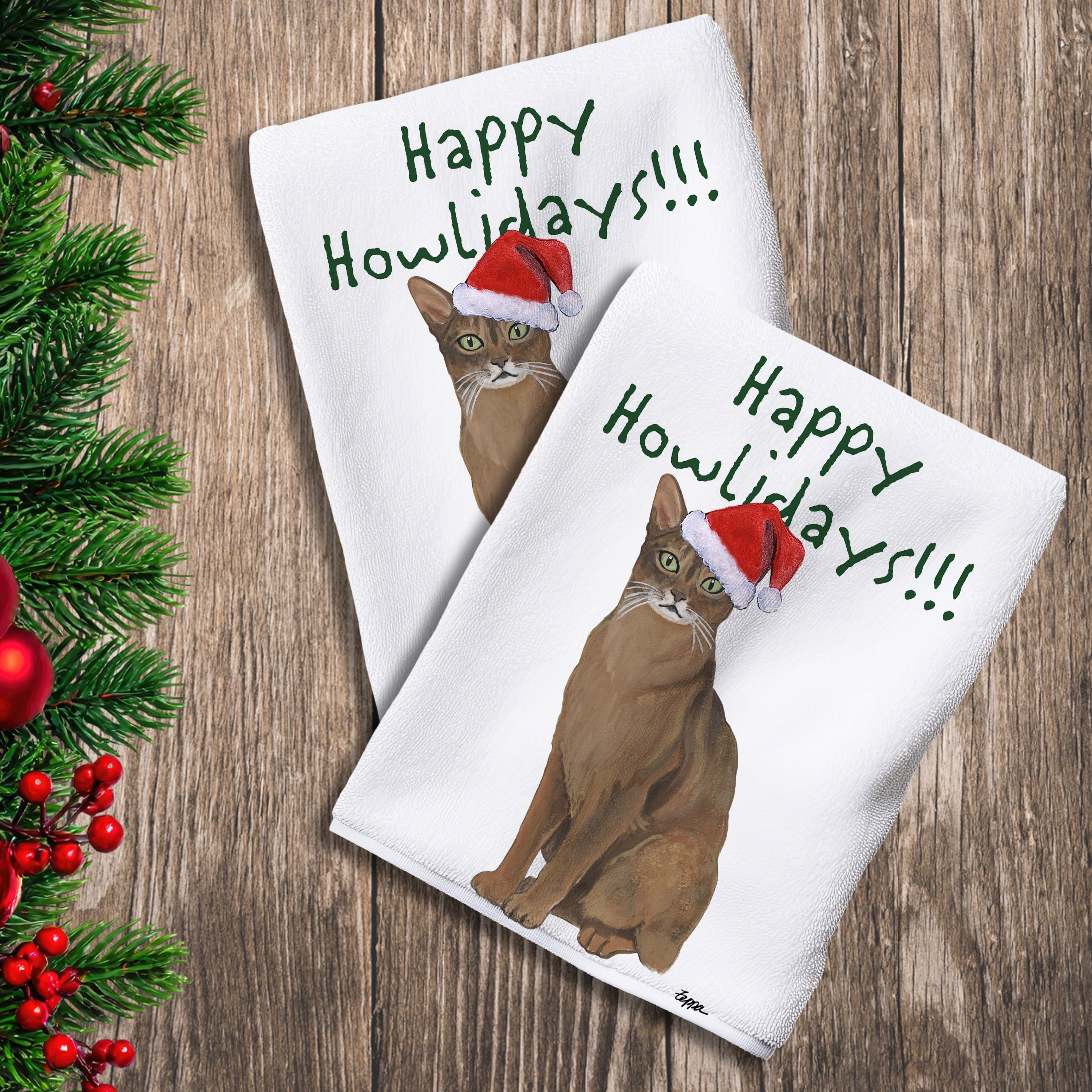 2 Kitchen Towels with an Abyssinian cat in a Santa Hat and Happy Howlidays text.
