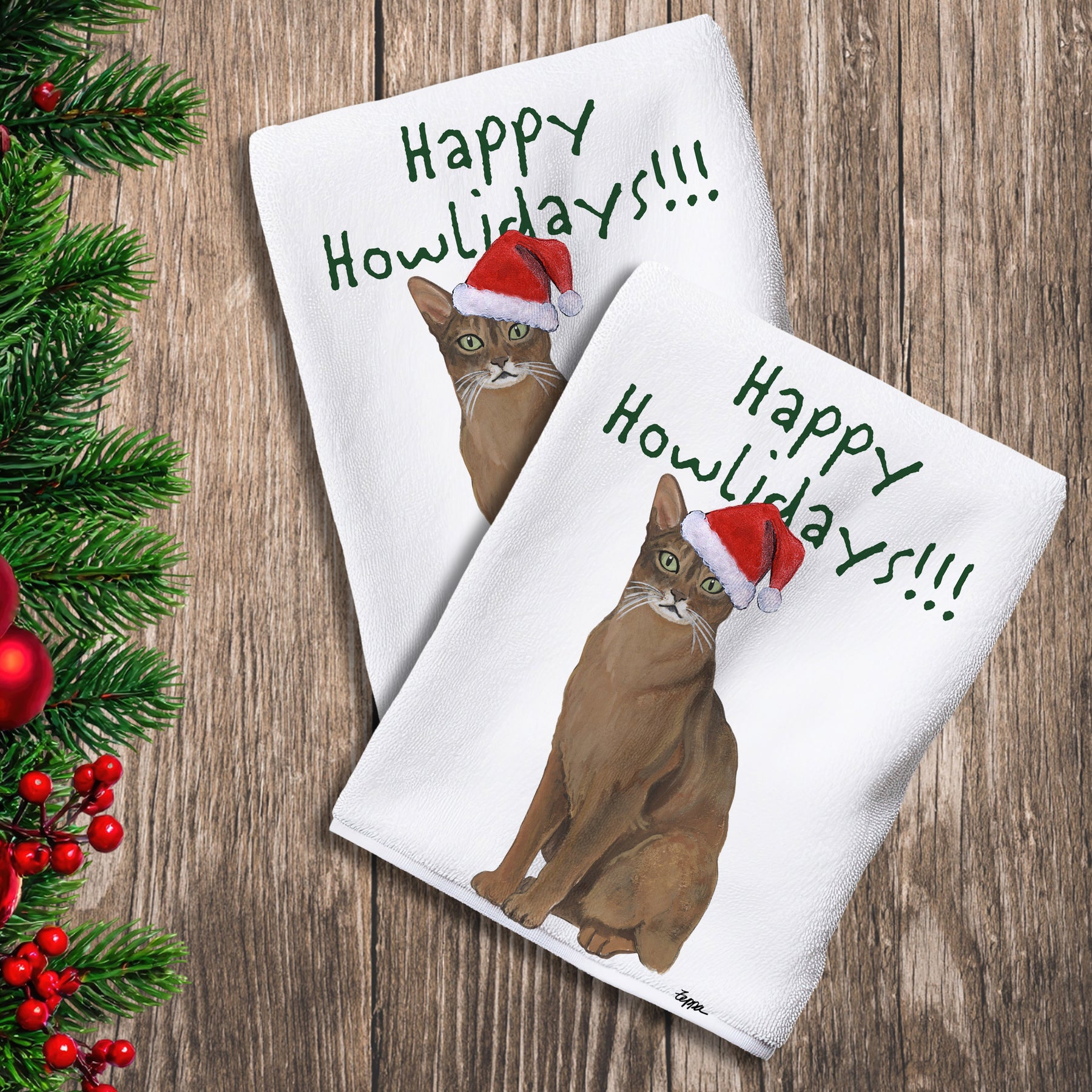 2 Kitchen Towels with an Abyssinian cat in a Santa Hat and Happy Howlidays text.

