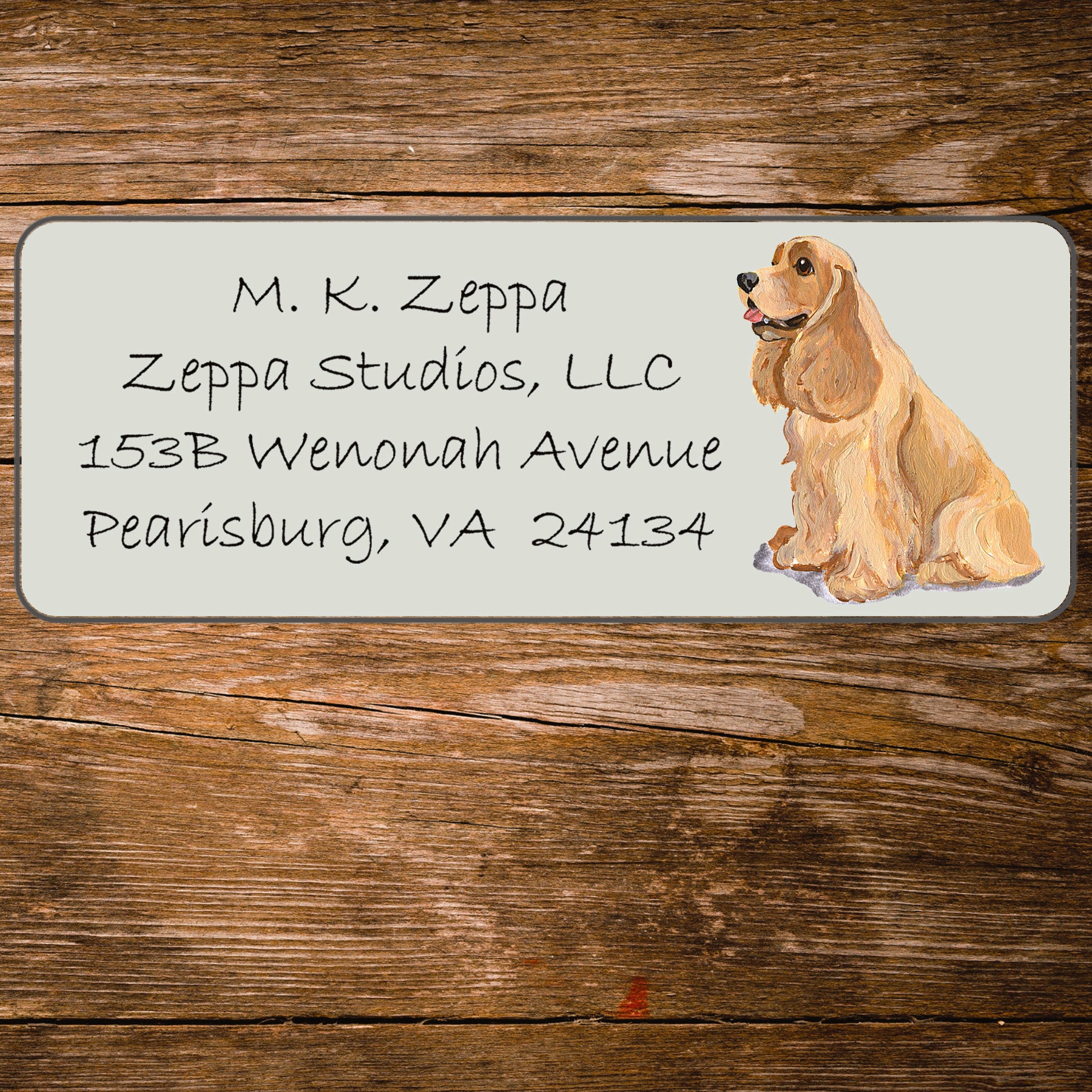 Address label with a Cocker Spaniel illustration and contact information on a wooden surface