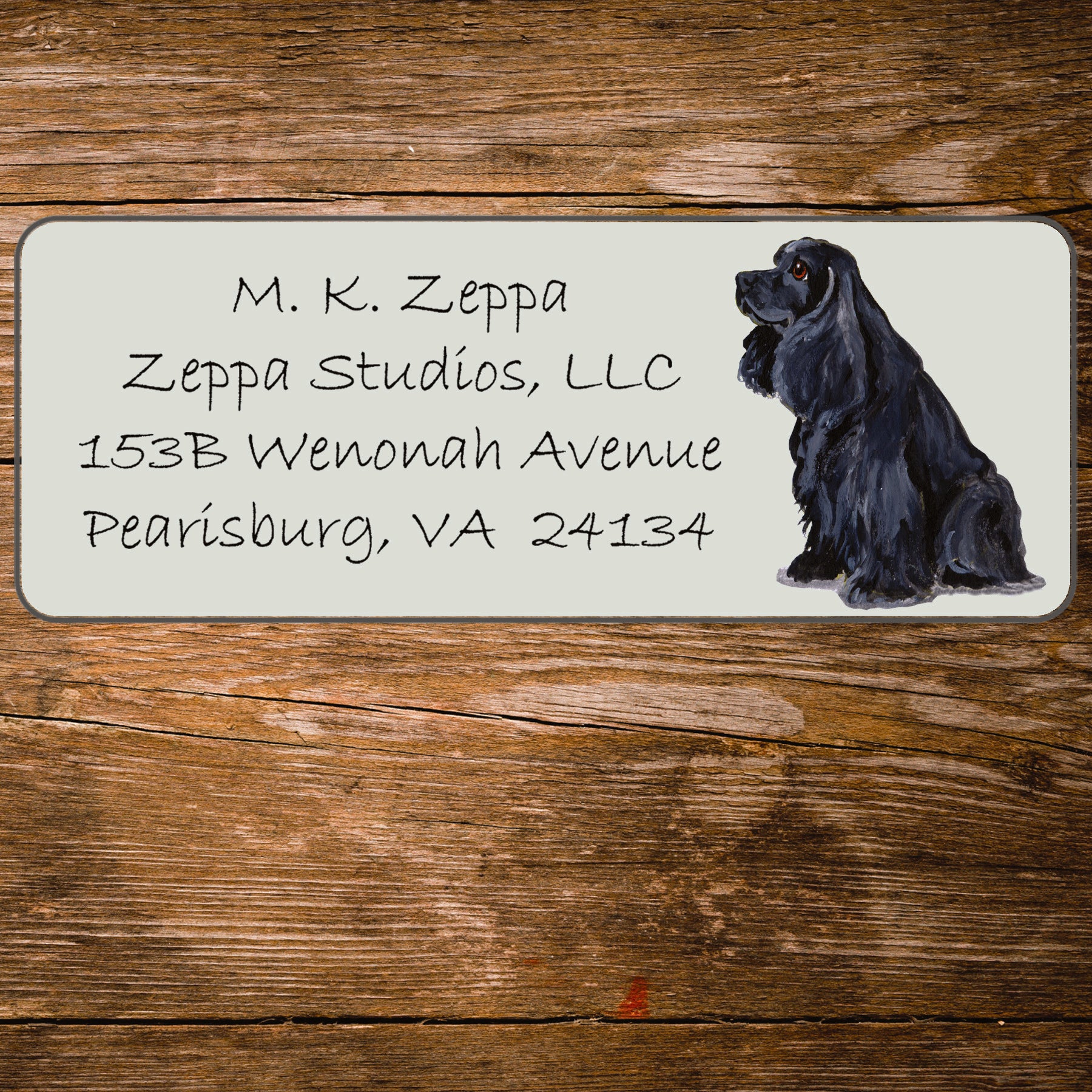 Address label with a Cocker Spaniel illustration and contact information on a wooden surface