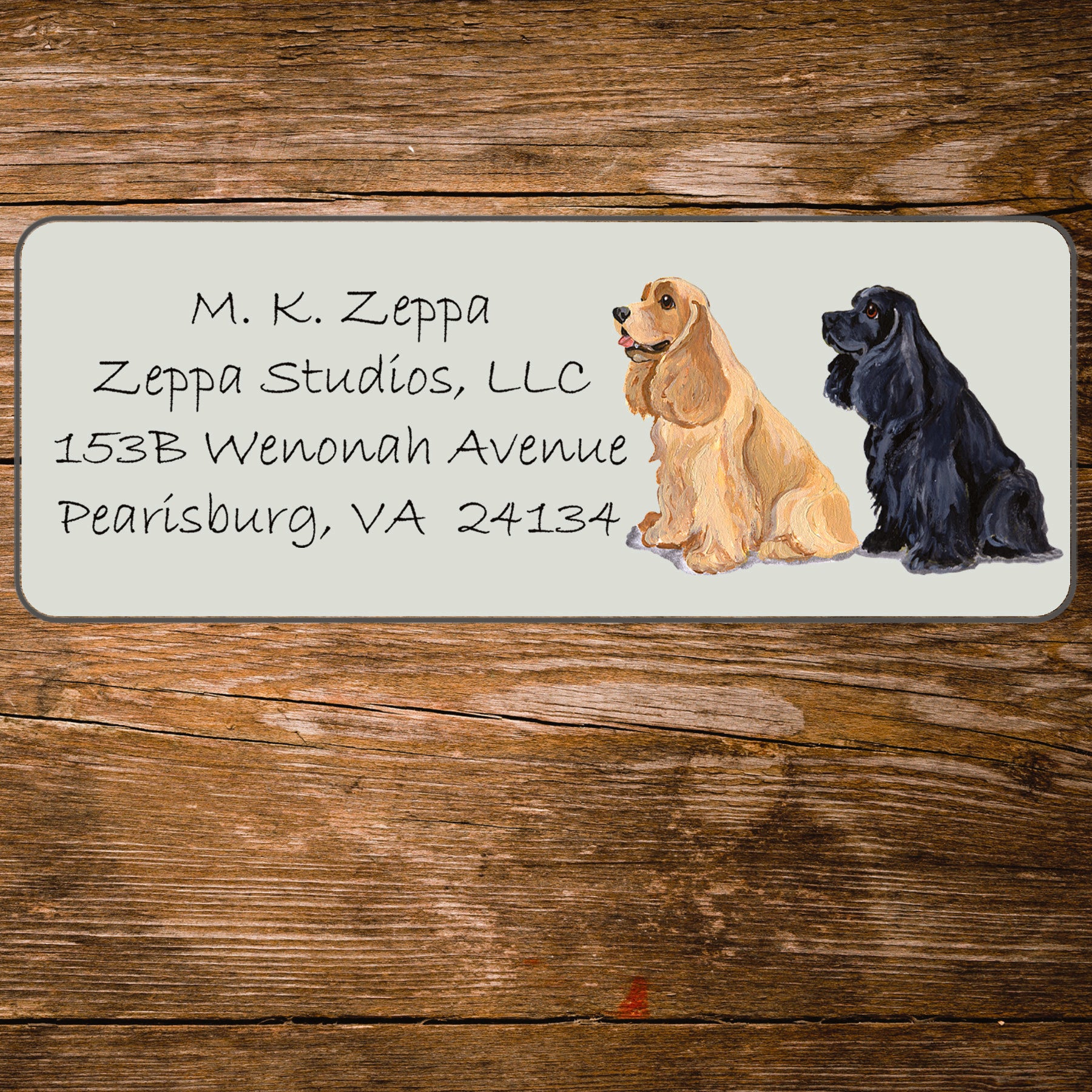 Address label with a Cocker Spaniel illustration and contact information on a wooden surface