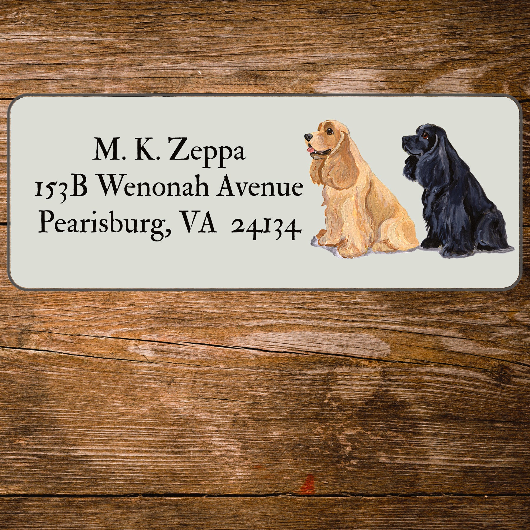 Address label with a Cocker Spaniel illustration and contact information on a wooden surface