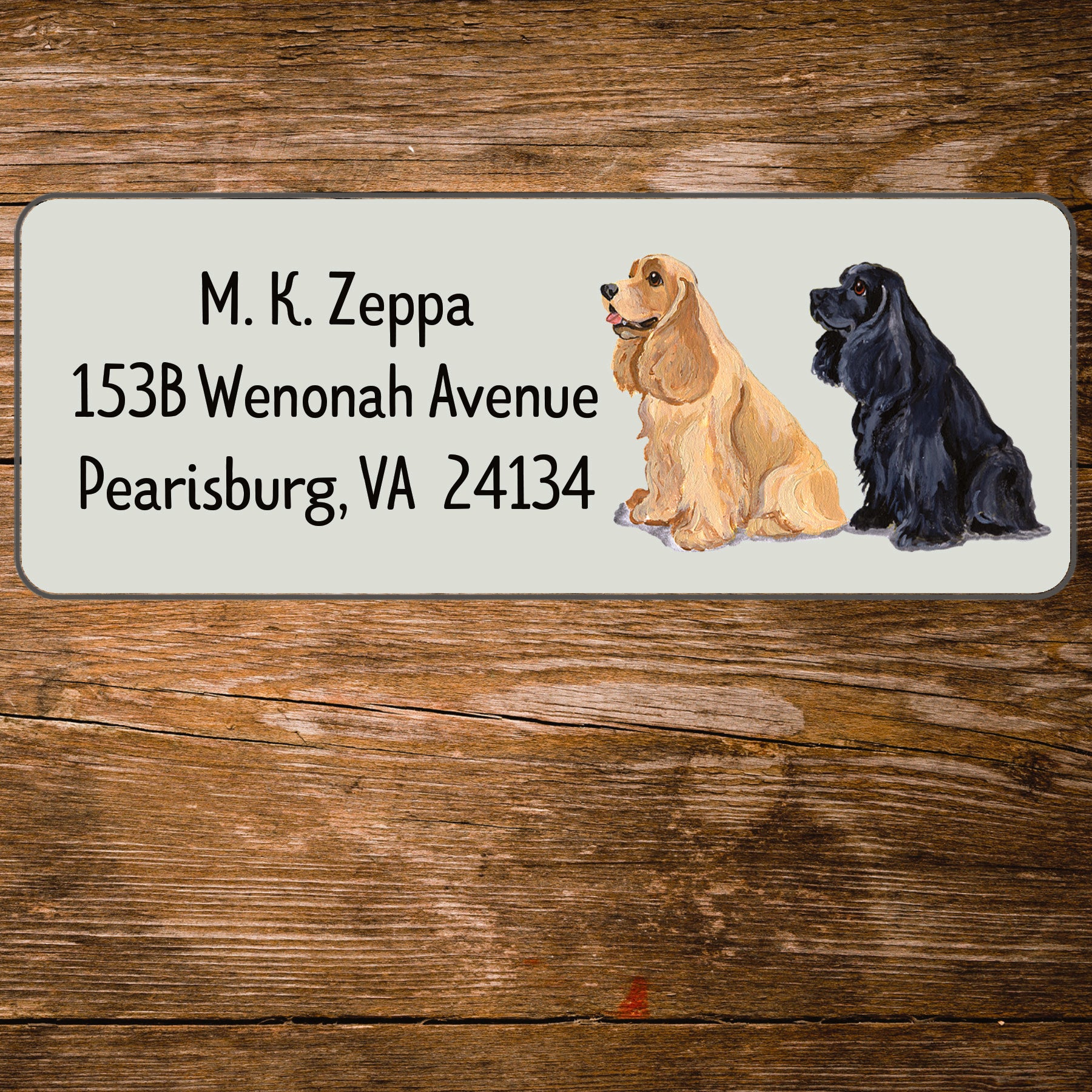 Address label with a Cocker Spaniel illustration and contact information on a wooden surface