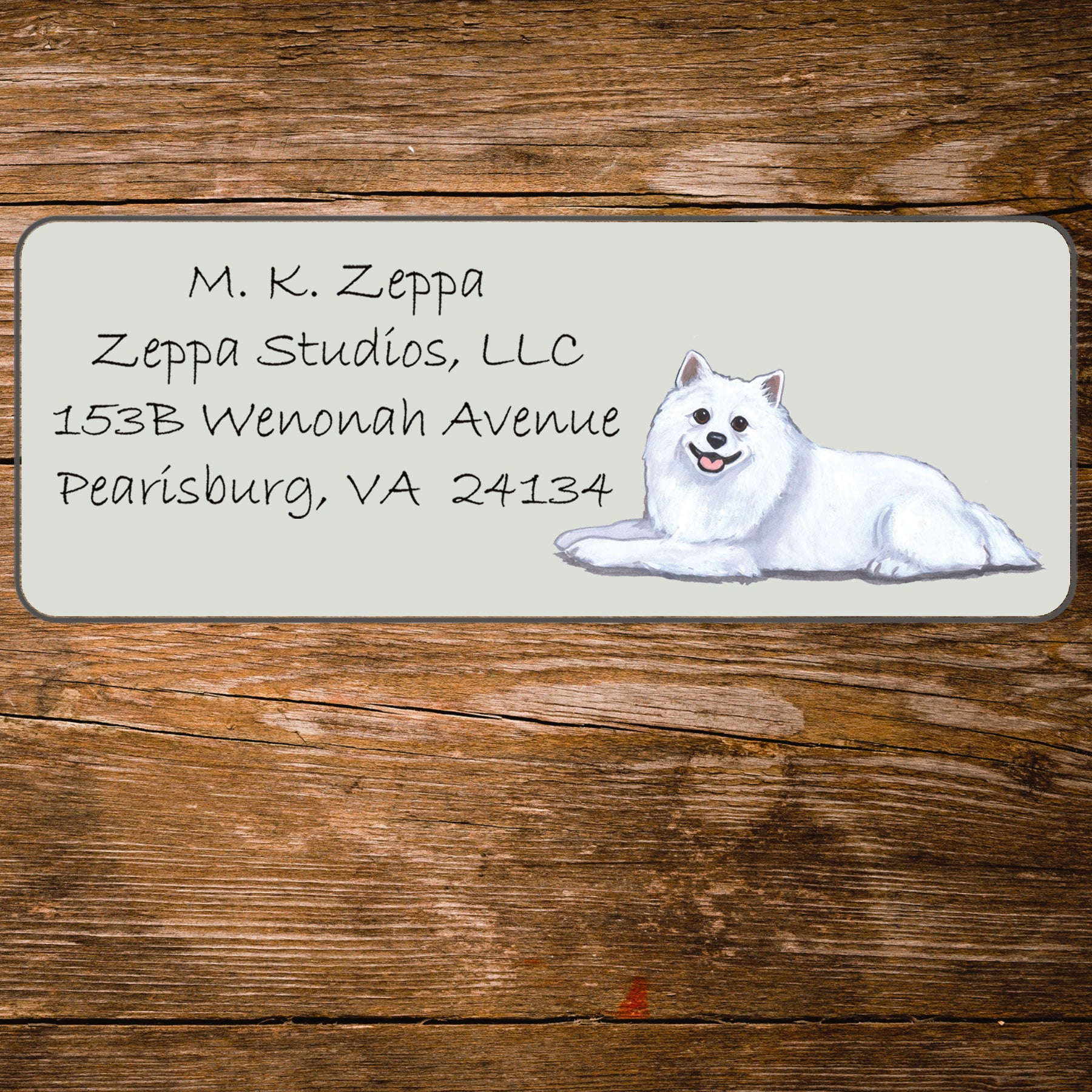 Return address label with an American Eskimo Dog illustration on a wooden surface