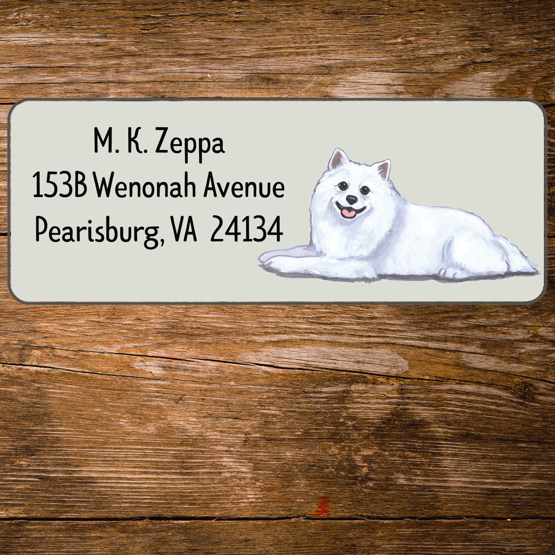 Return address label with an American Eskimo Dog illustration on a wooden surface