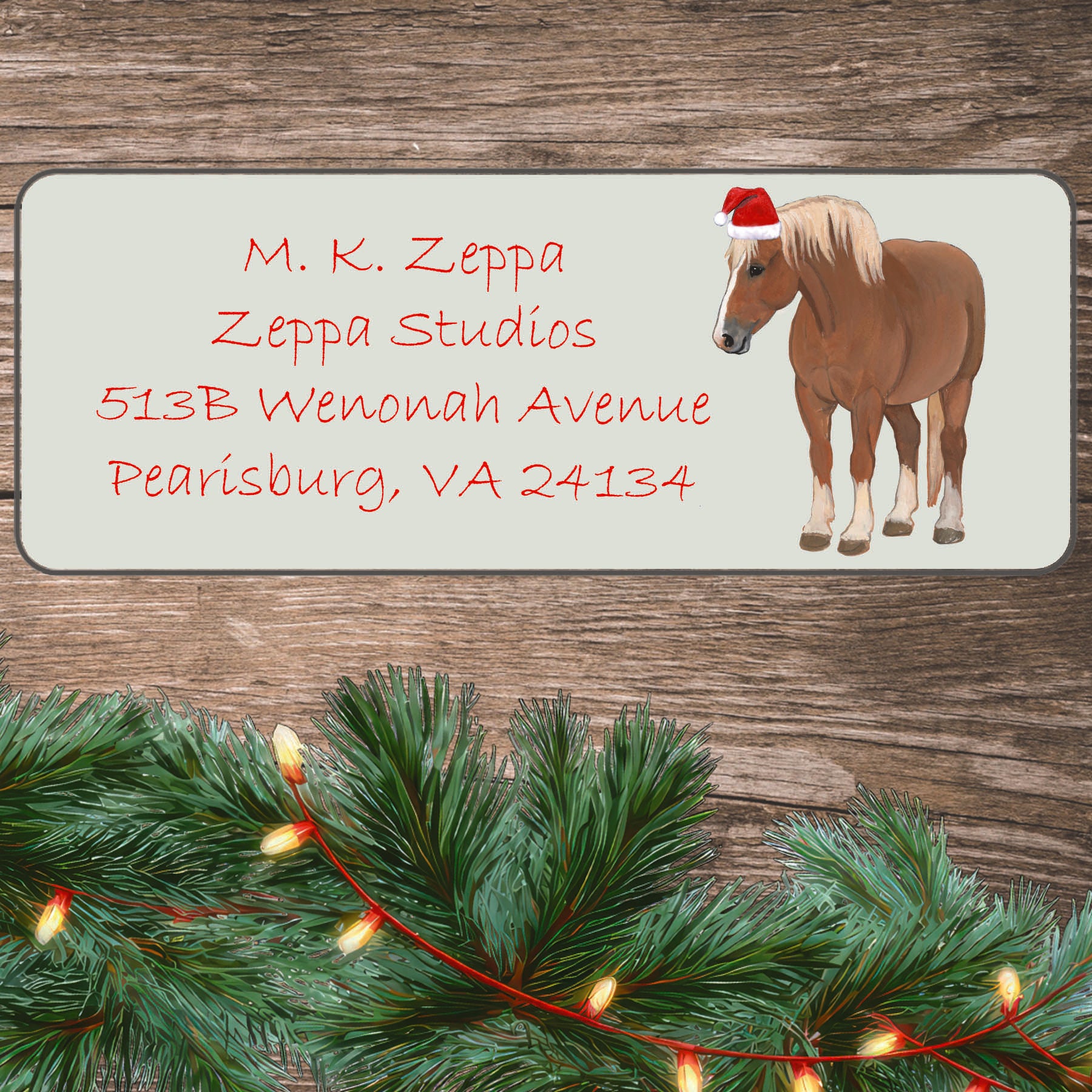 A Belgian Horse in a Santa Hat on an ivory return address label set off by a wood surface with holiday greenery background.