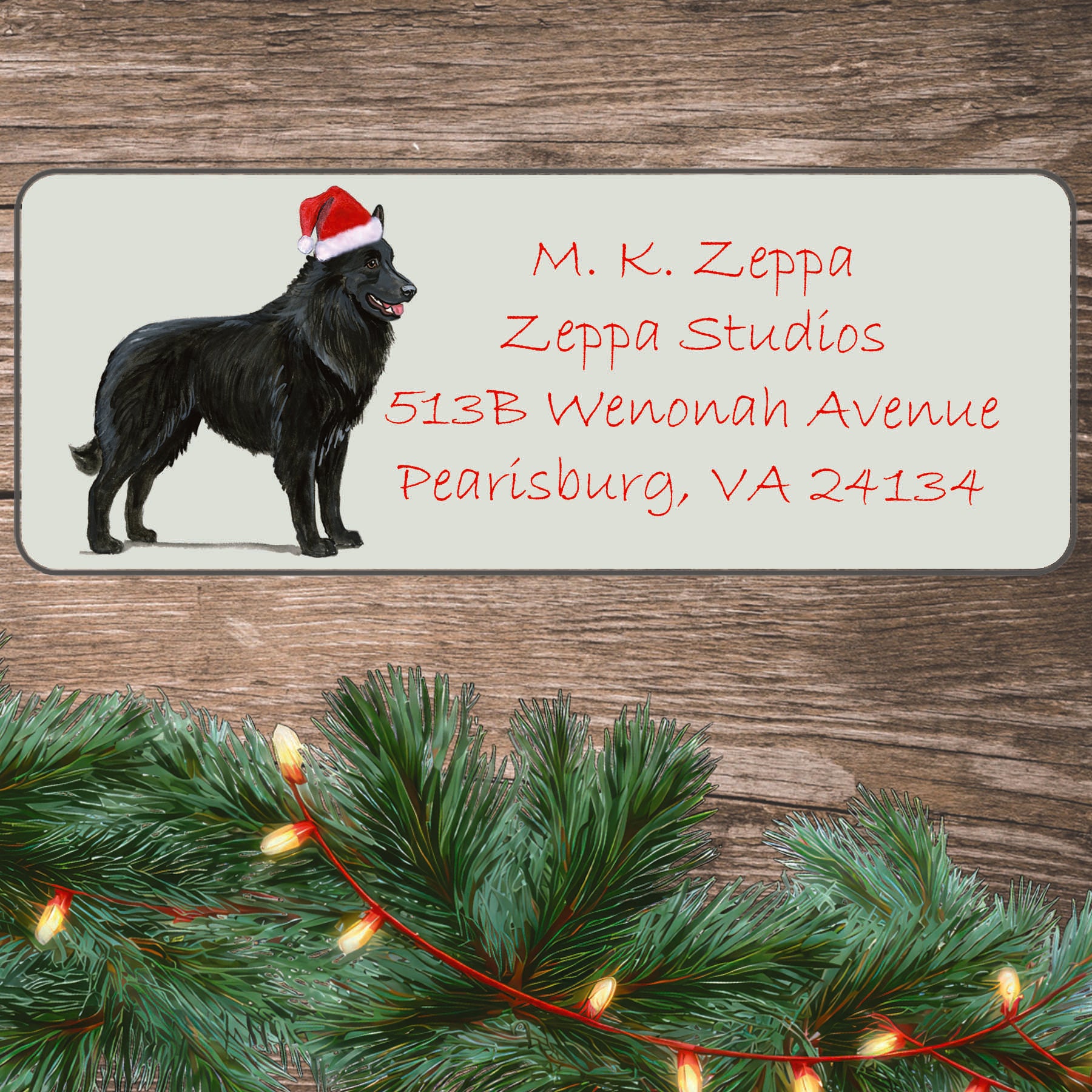 An illustration of a Belgian Shepherd wearing a Santa Hat on an ivory return address label set off by a wood surface with holiday greenery background.