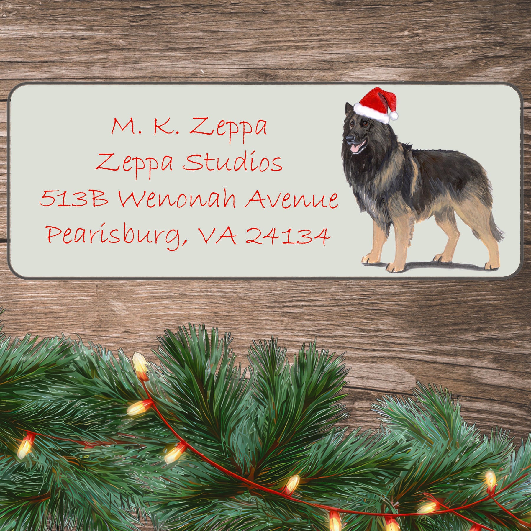 An illustration of a Belgian Tervuren wearing a Santa Hat on an ivory return address label set off by a wood surface with holiday greenery background.