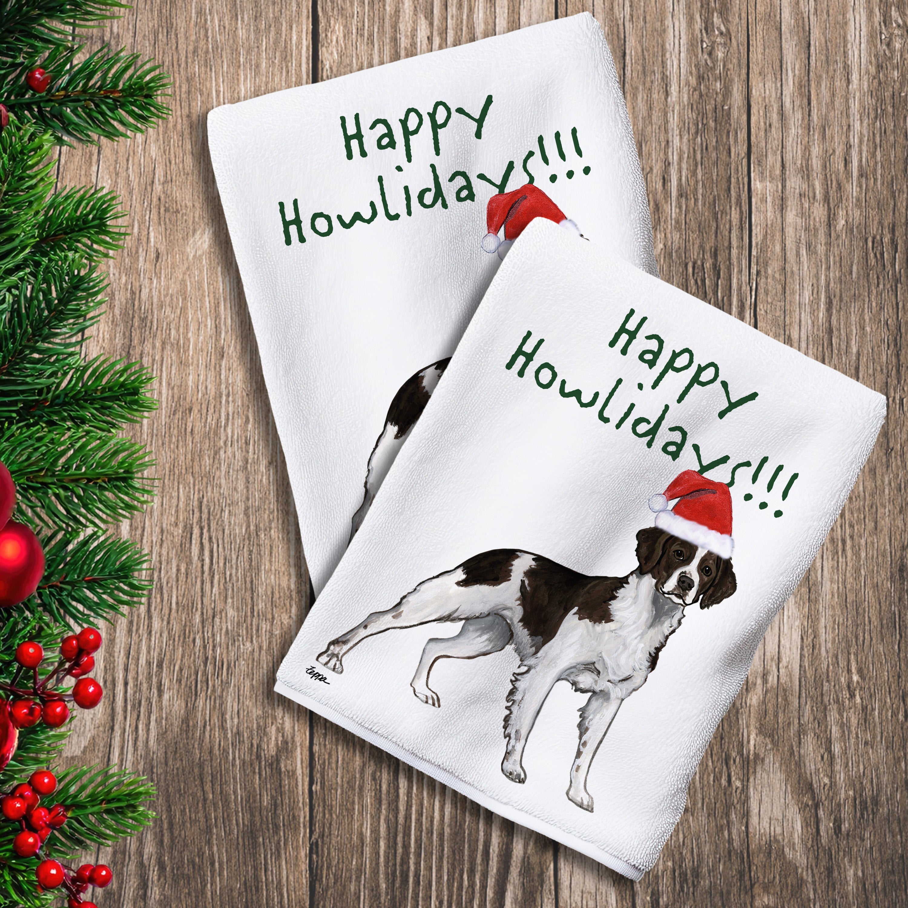 2 Kitchen Towels with a liver and white Brittany in a Santa Hat and Happy Howlidays text.