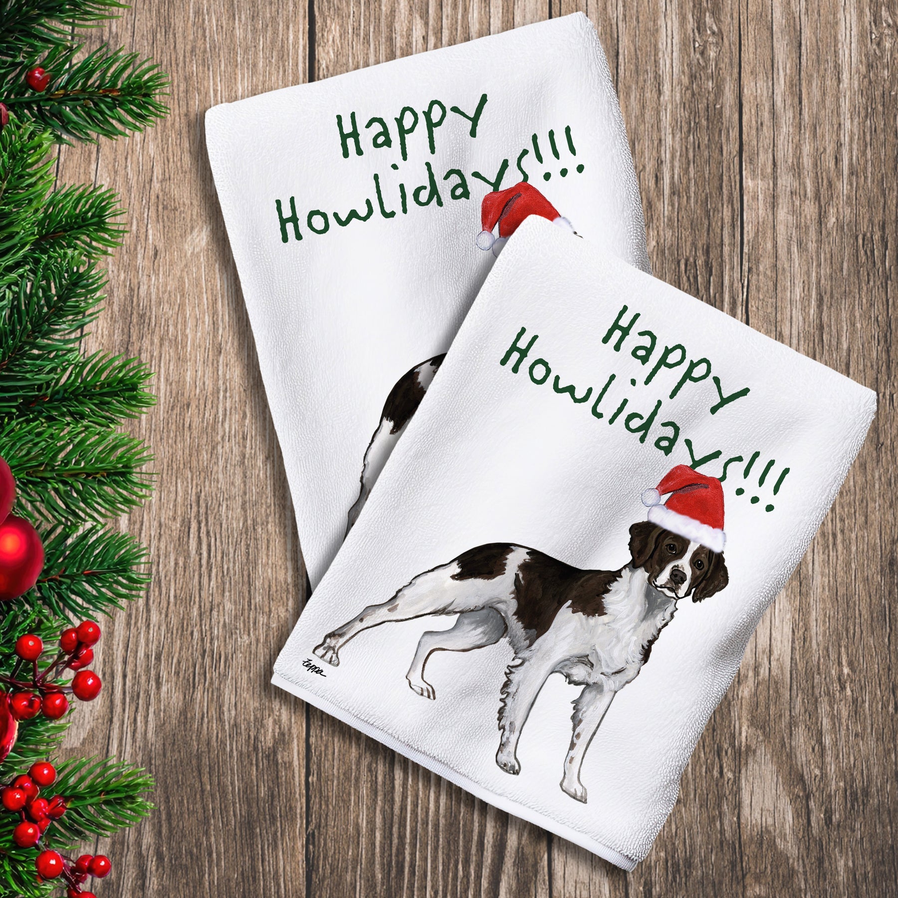 2 Kitchen Towels with a liver and white Brittany in a Santa Hat and Happy Howlidays text.