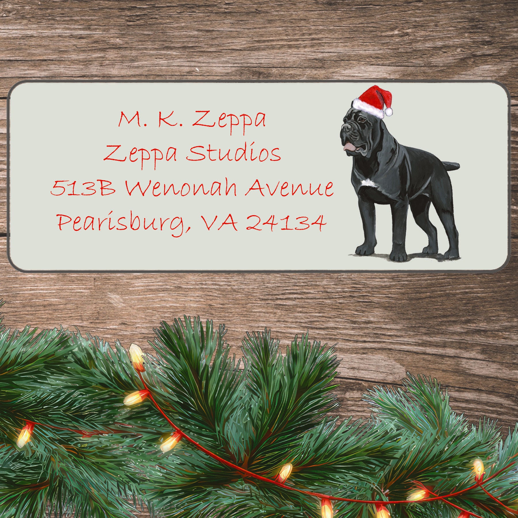 An illustration of a Cane Corso wearing a Santa Hat on an ivory return address label set off by a wood surface with holiday greenery background.