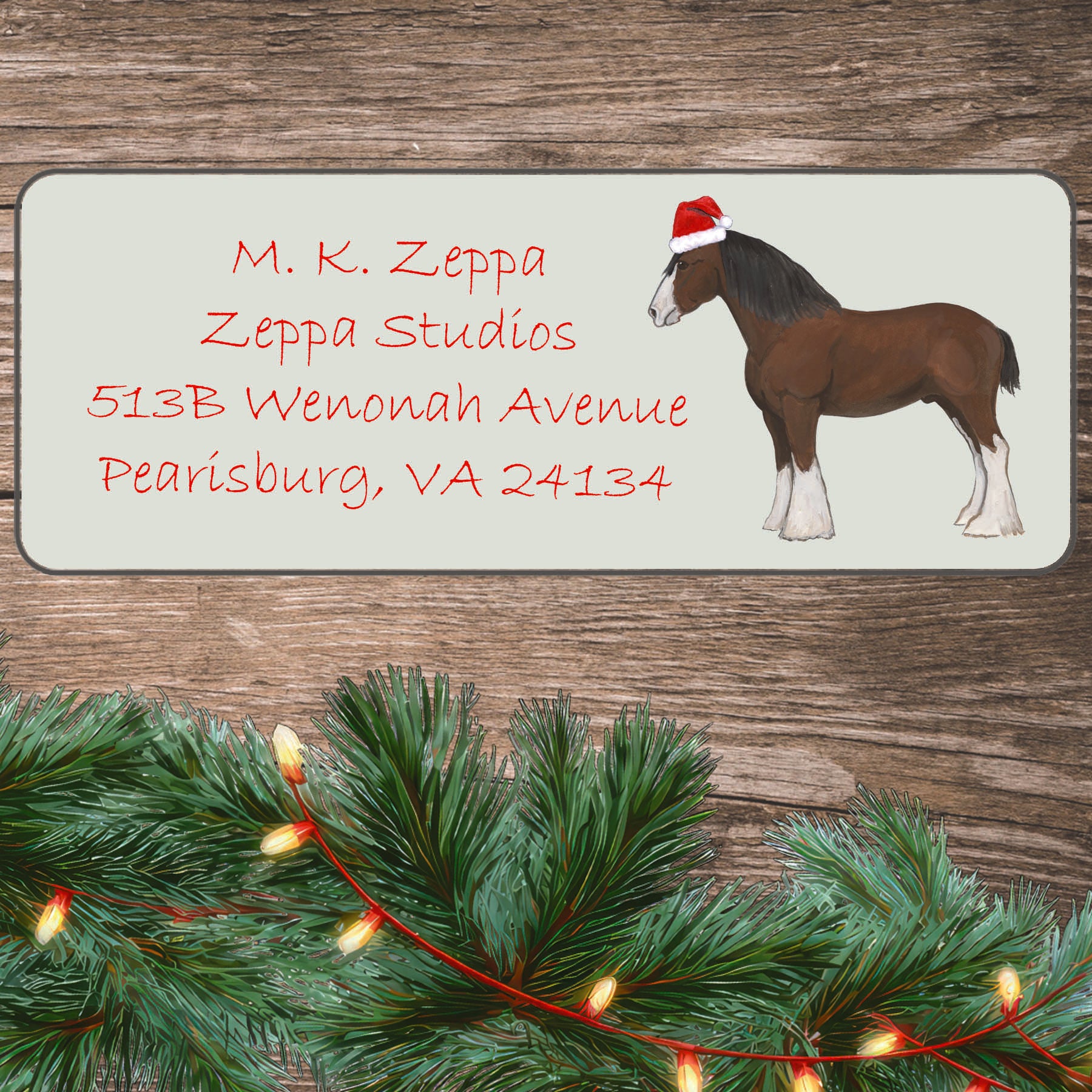 A Clydesdale Horse in a Santa Hat illustration on an ivory return address label set off by a wood surface with holiday greenery background.
