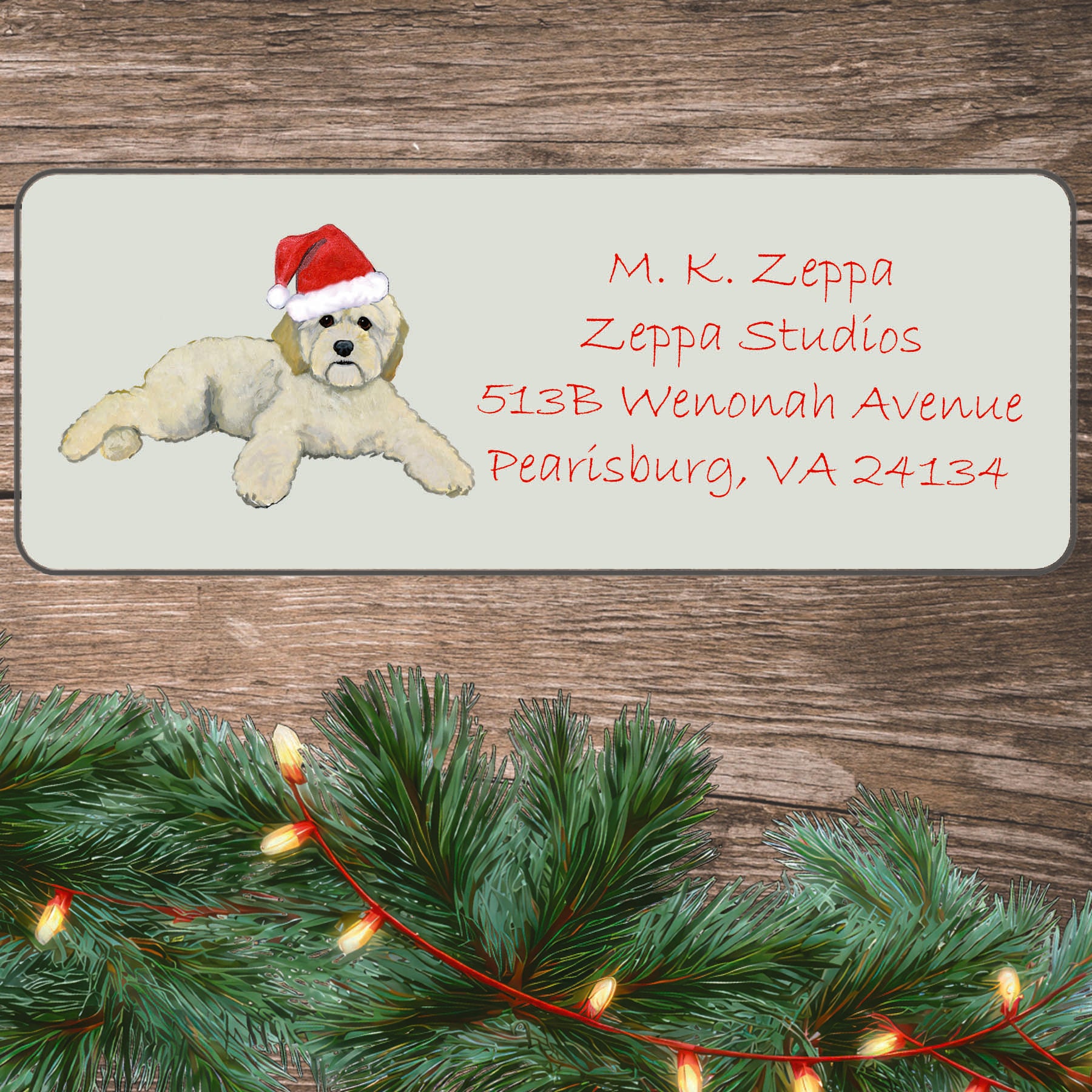 An illustration of a Cockapoo wearing a Santa Hat on an ivory return address label set off by a wood surface with holiday greenery background.