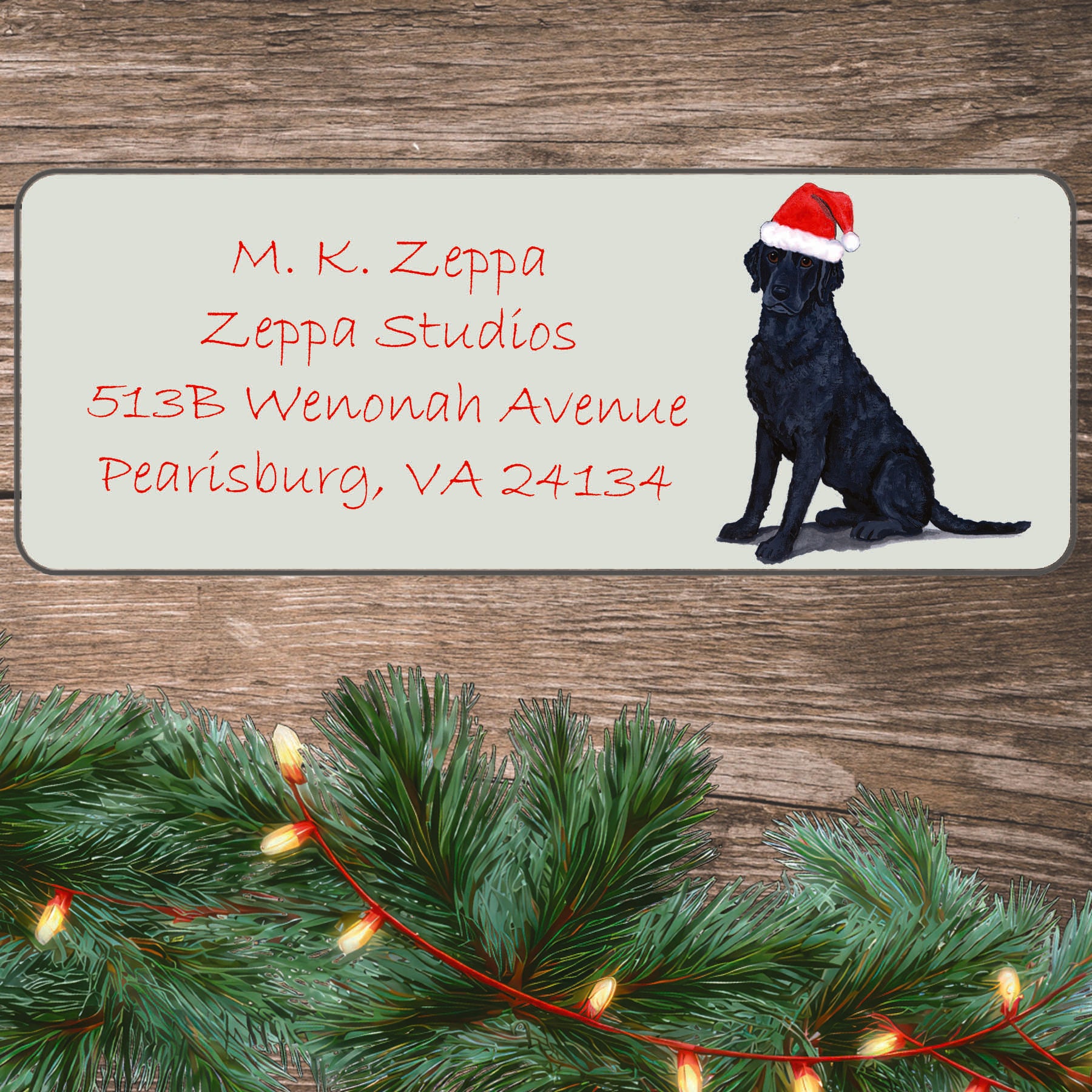 An illustration of a Curly-Coated Retriever wearing a Santa Hat on an ivory return address label set off by a wood surface with holiday greenery background.