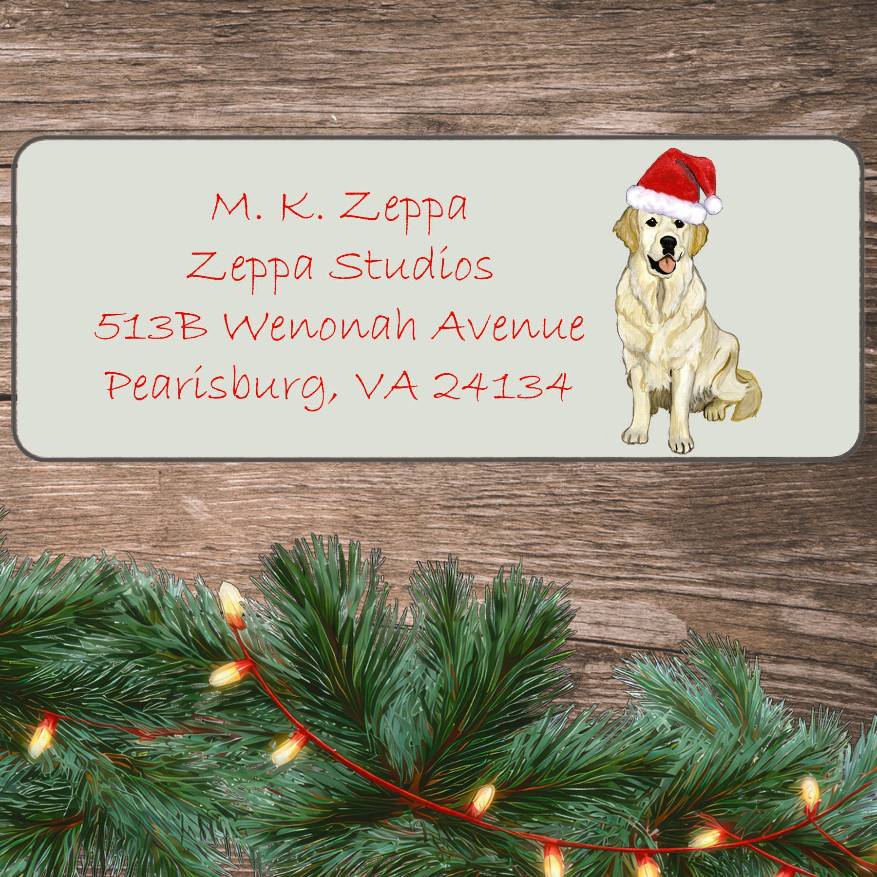 An illustration of an English cream Golden Retriever wearing a Santa Hat on an ivory return address label set off by a wood surface with holiday greenery background.