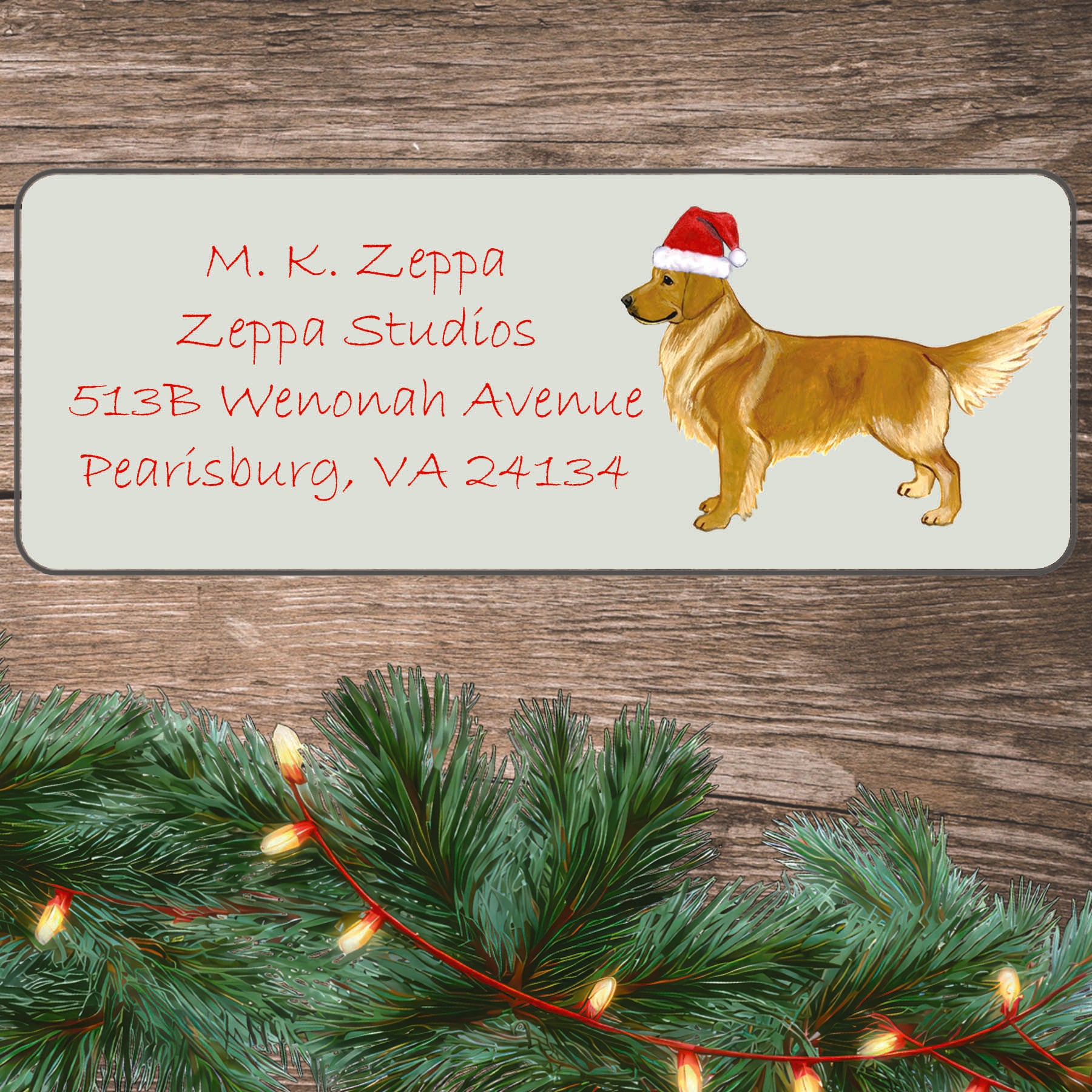 An illustration of a standing Golden Retriever wearing a Santa Hat on an ivory return address label set off by a wood surface with holiday greenery background.