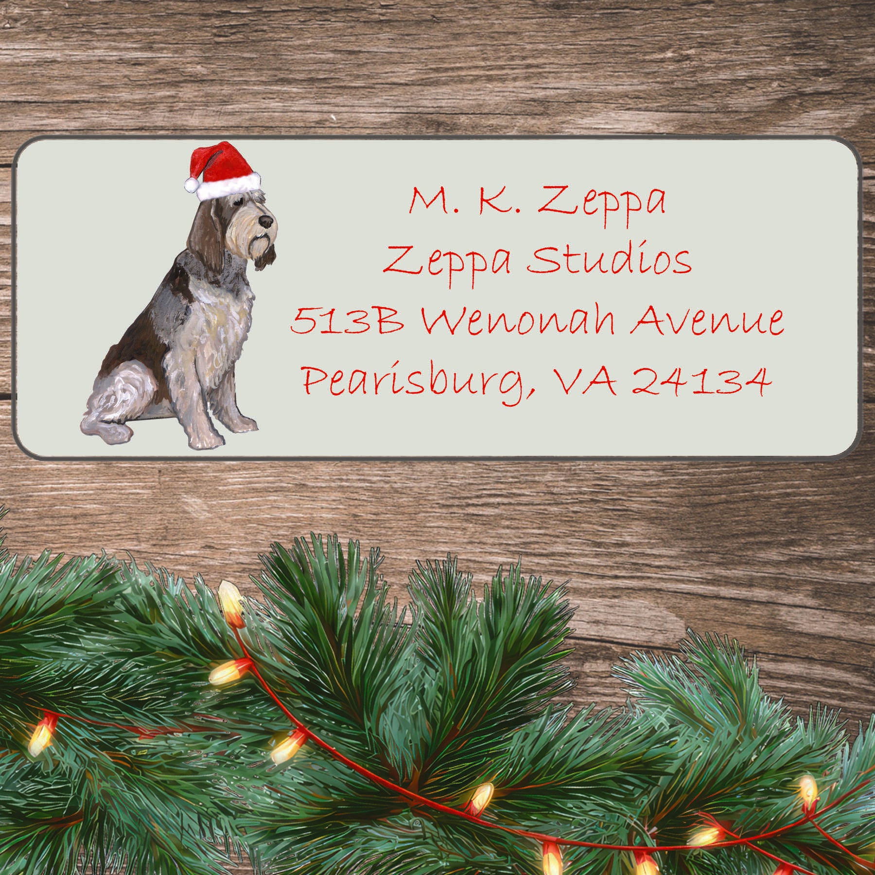 An illustration of an Italian Spinone  wearing a Santa Hat on an ivory return address label set off by a wood surface with holiday greenery background.
