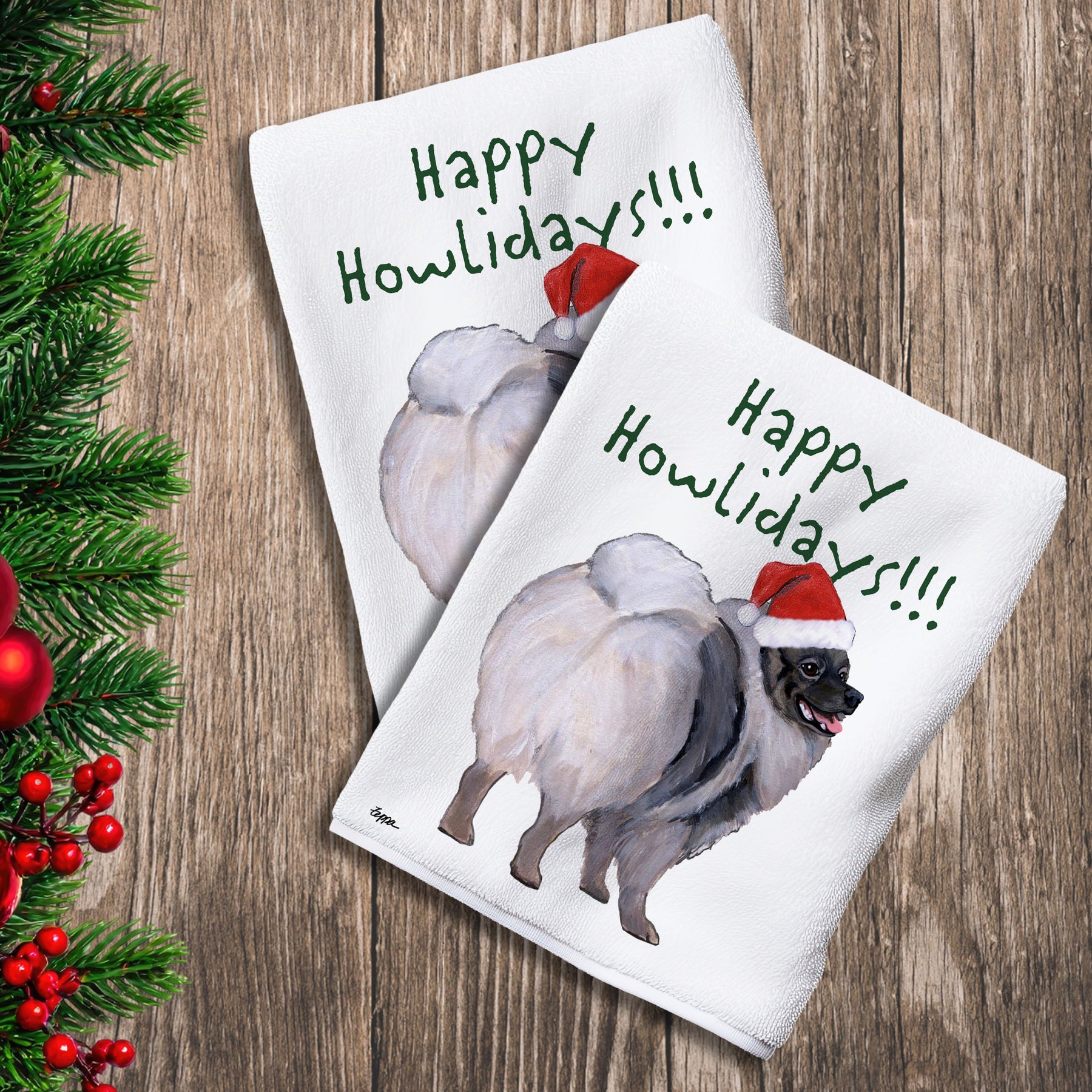 2 Kitchen Towels with a Keeshond in a Santa Hat and Happy Howlidays text.