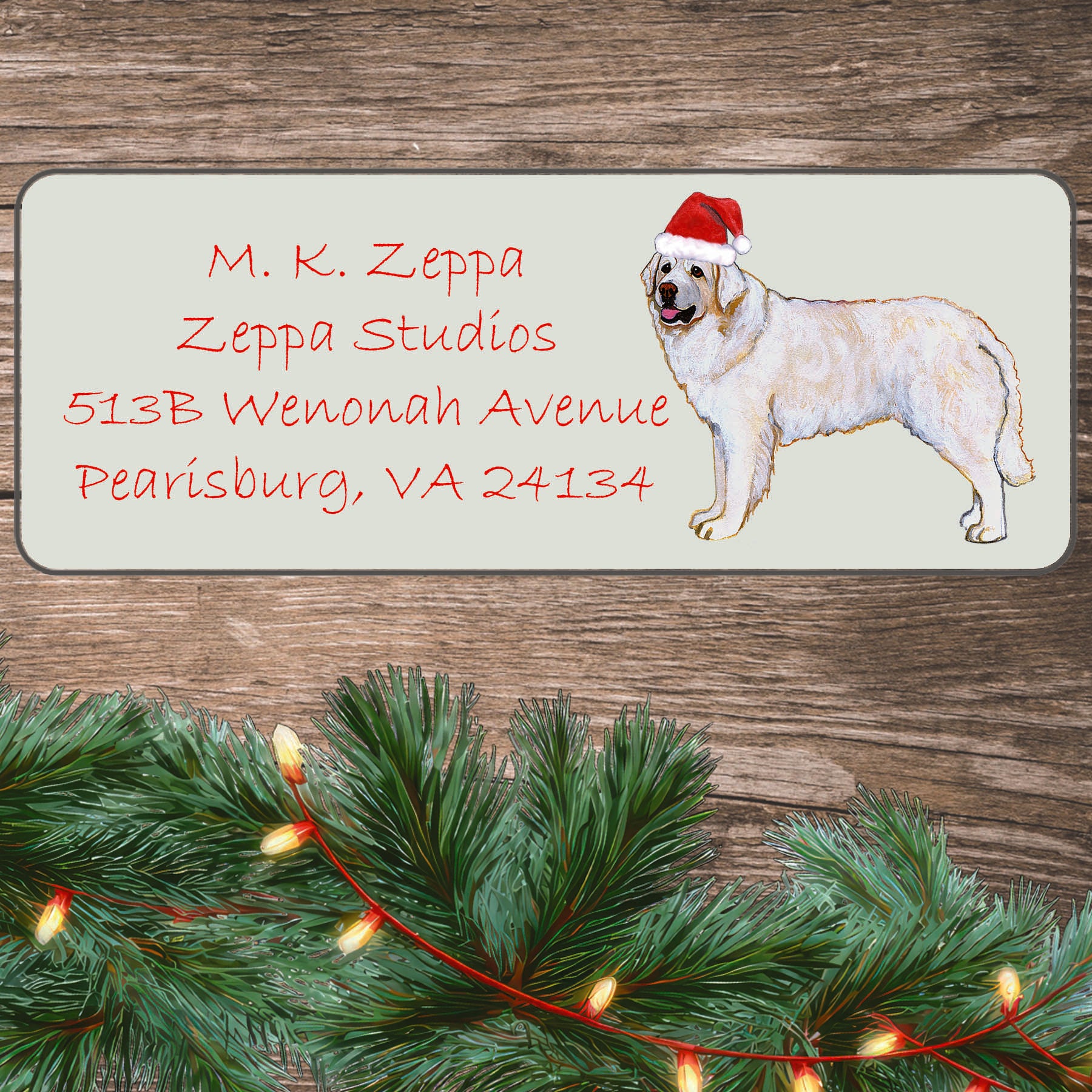 An illustration of a Kuvasz wearing a Santa Hat on an ivory return address label set off by a wood surface with holiday greenery background.