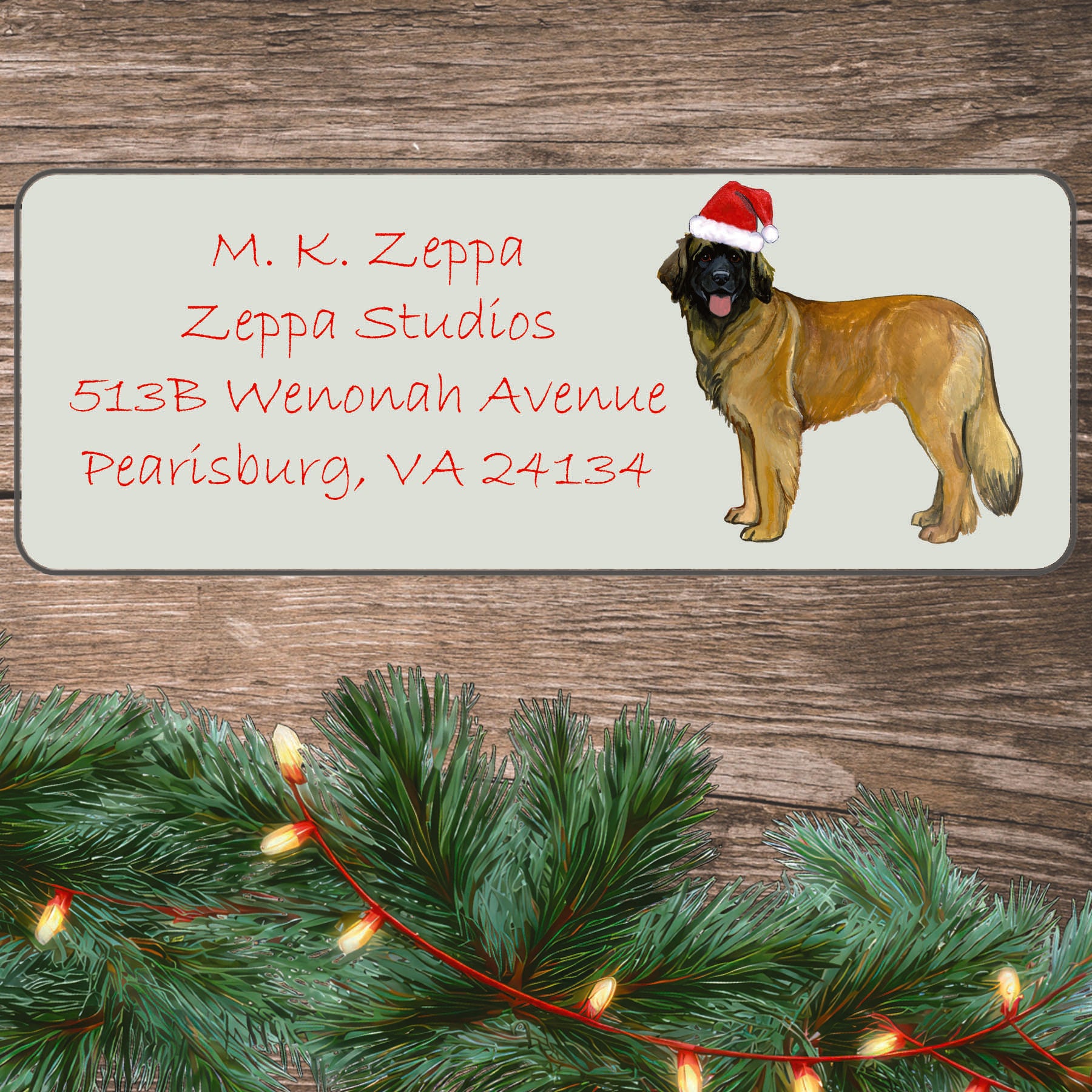 An illustration of a Leonberger wearing a Santa Hat on an ivory return address label set off by a wood surface with holiday greenery background.
