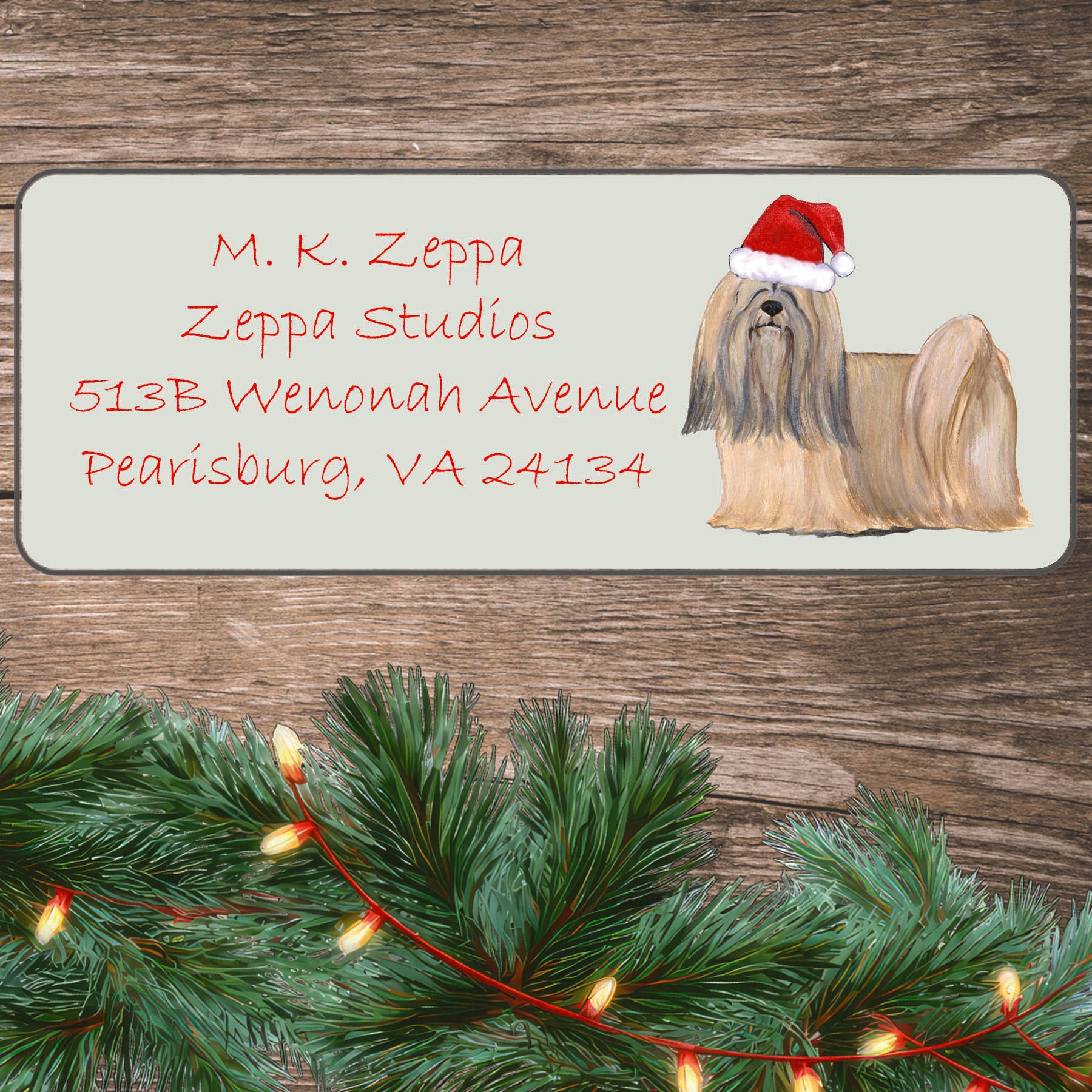 An illustration of a Lhasa Apso wearing a Santa Hat on an ivory return address label set off by a wood surface with holiday greenery background.