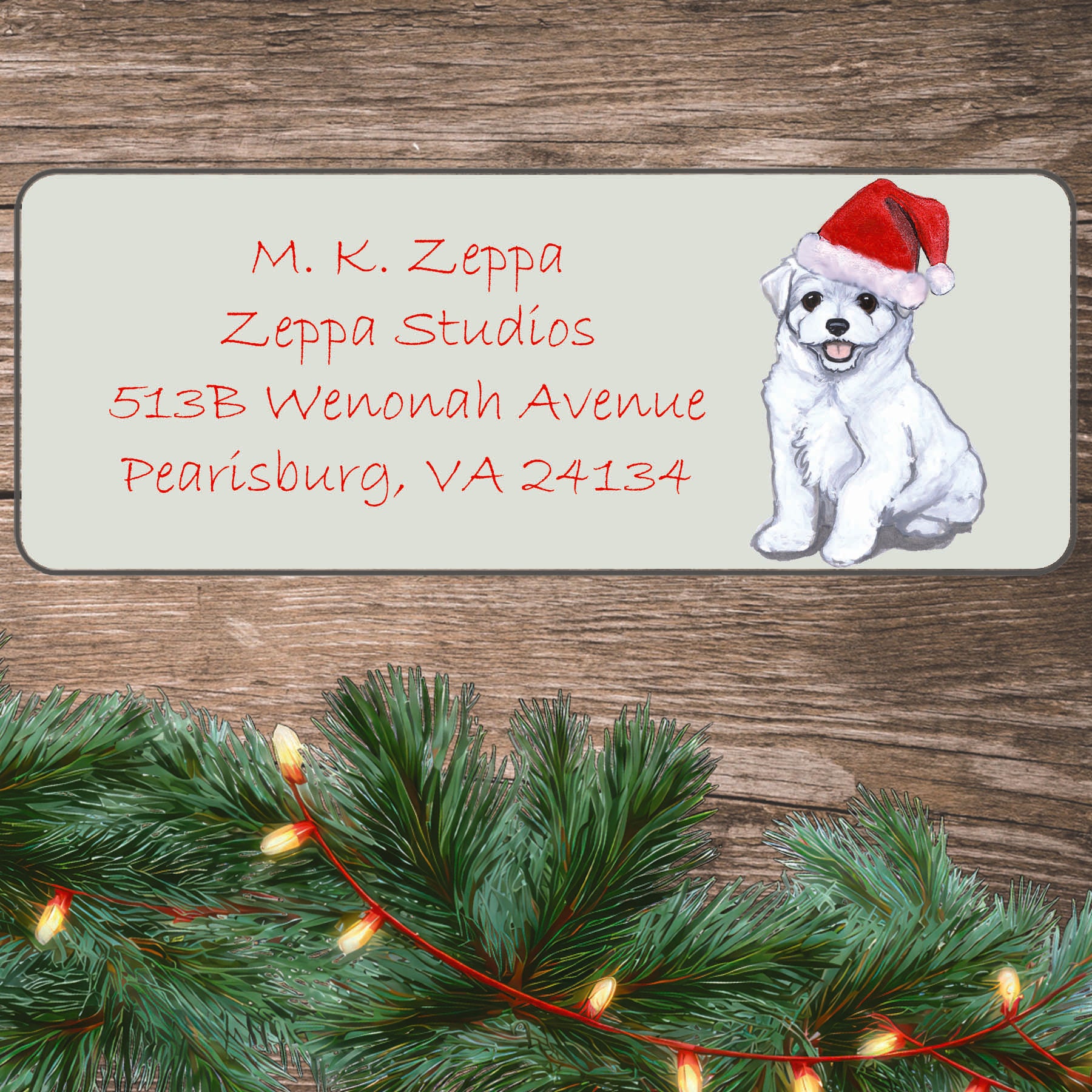 An illustration of a Maltese puppy wearing a Santa Hat on an ivory return address label set off by a wood surface with holiday greenery background.