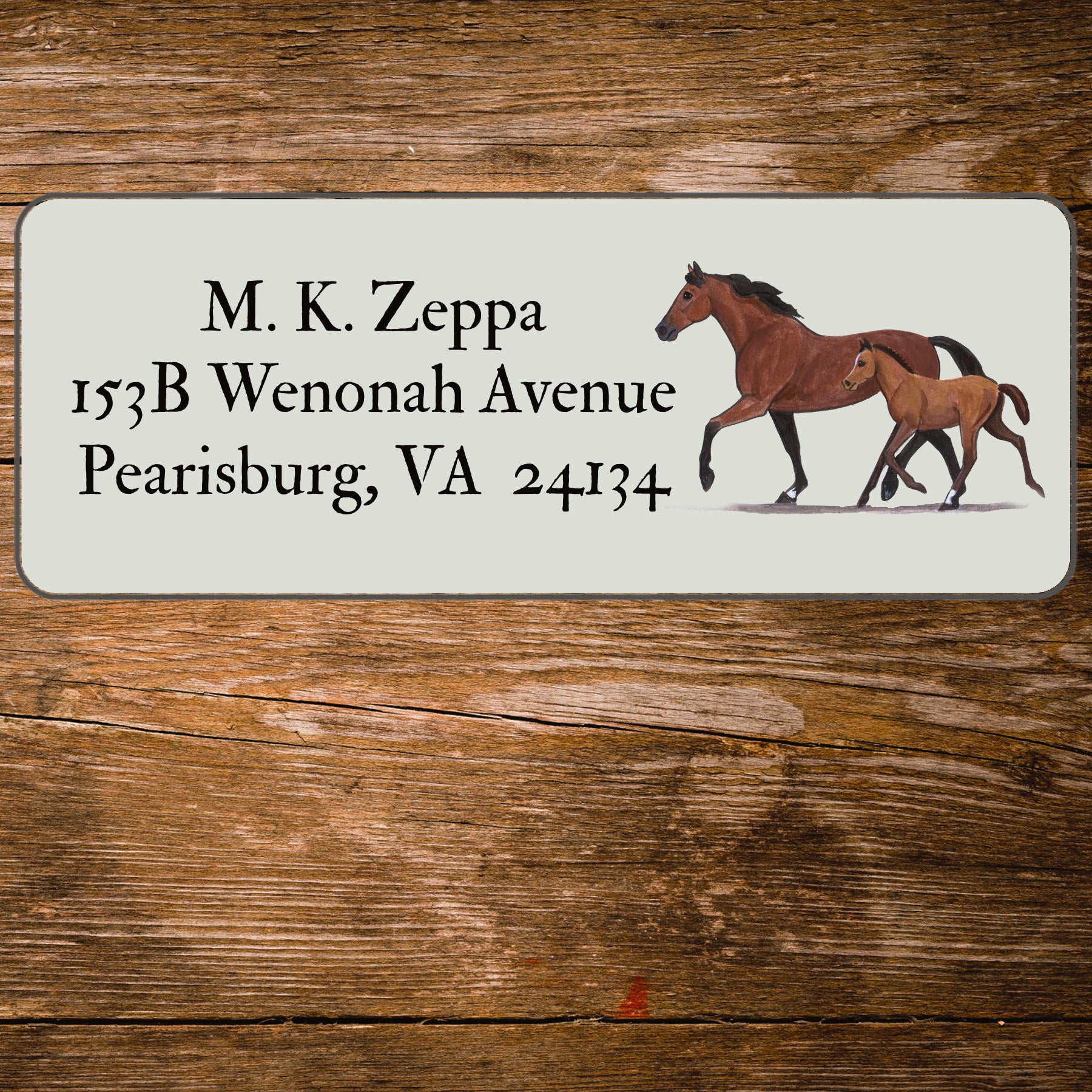 Address label with a mare and foal illustration on a wooden background