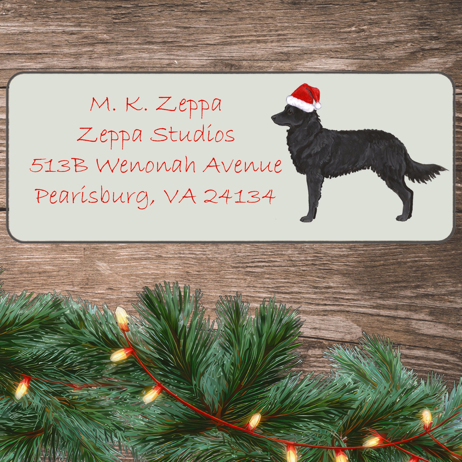An illustration of a Mudi wearing a Santa Hat on an ivory return address label set off by a wood surface with holiday greenery background.