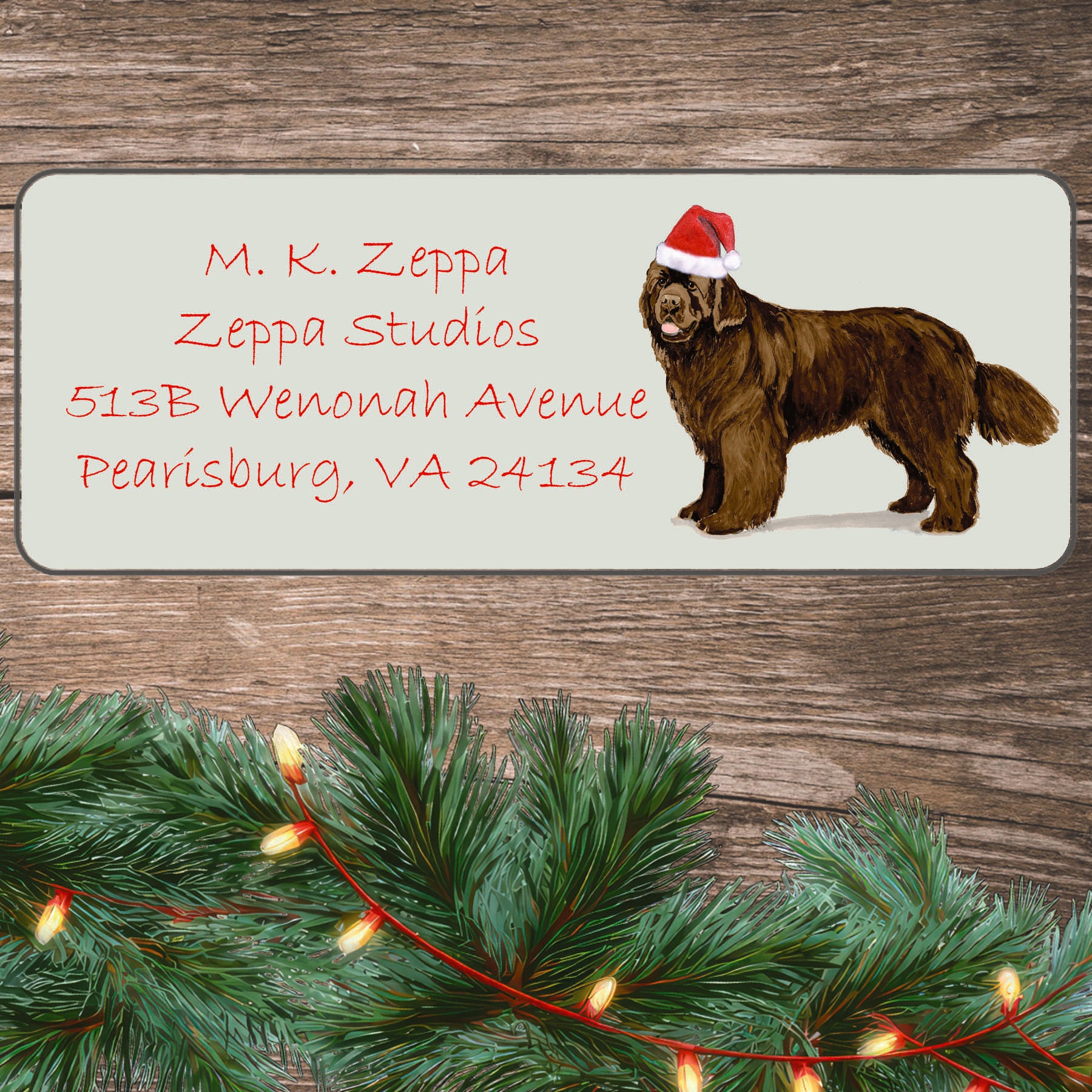 An illustration of a brown Newfoundland wearing a Santa Hat on an ivory return address label set off by a wood surface with holiday greenery background.