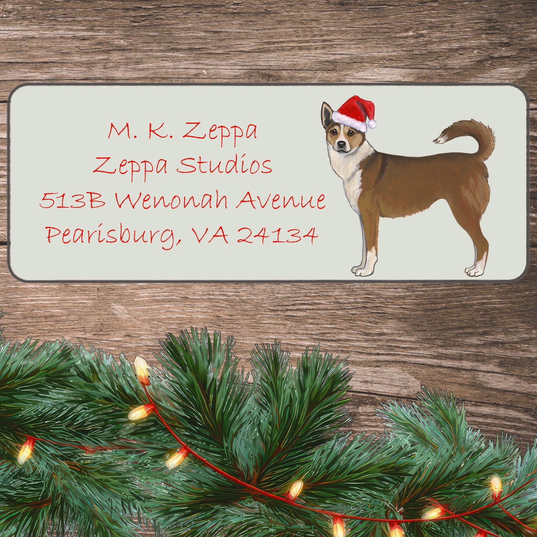 An illustration of a Norwegian Lundehund wearing a Santa Hat on an ivory return address label set off by a wood surface with holiday greenery background.