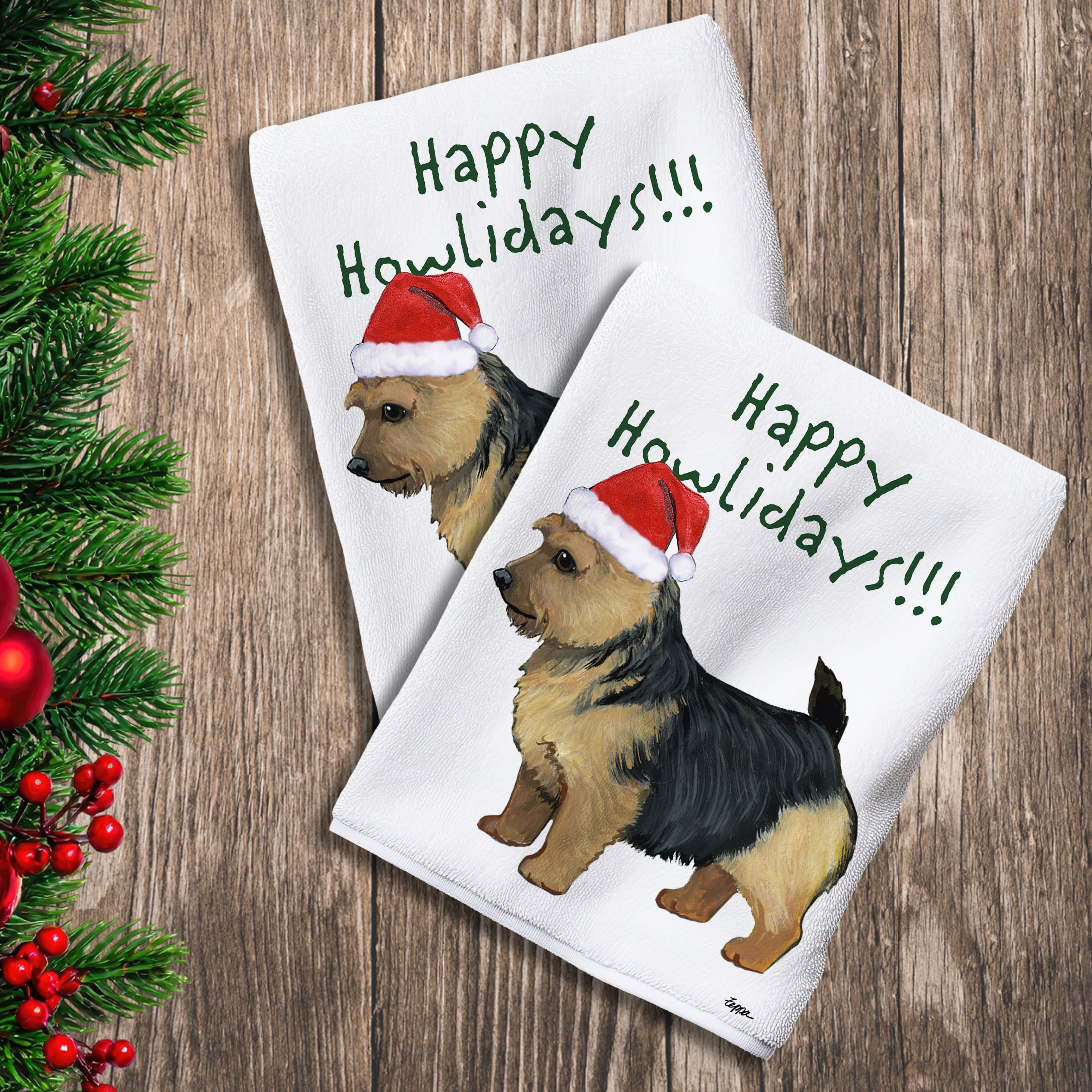 2 Kitchen Towels with a black and tan Norwich Terrier in a Santa Hat and Happy Howlidays text.
