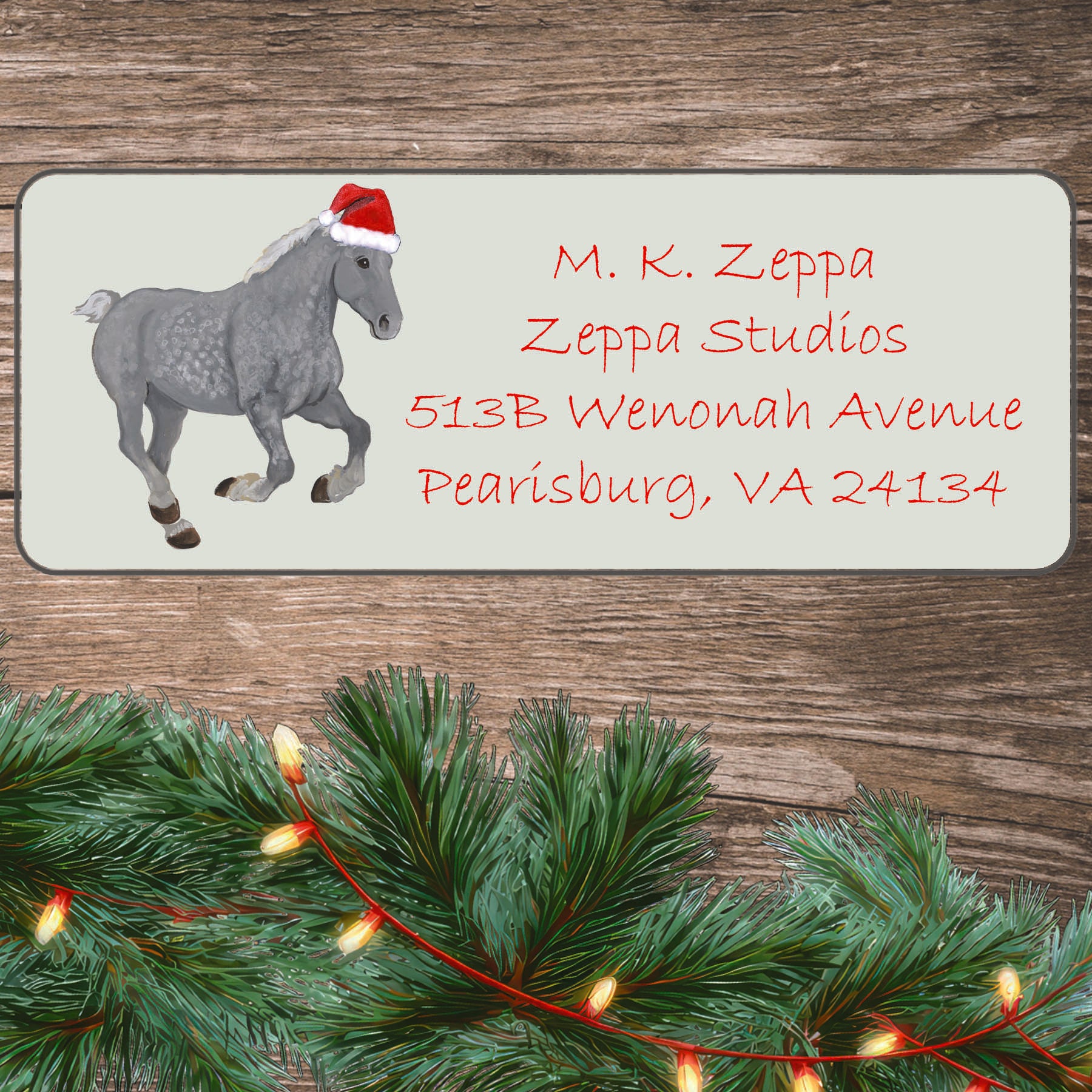 A Percheron Horse in a Santa Hat on an ivory return address label set off by a wood surface with holiday greenery background.