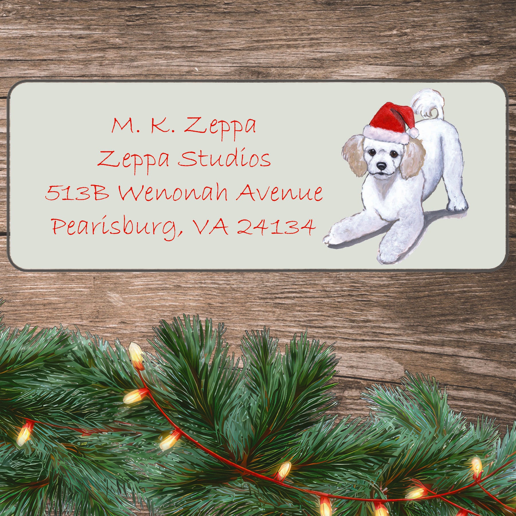 An illustration of a Poodle puppy wearing a Santa Hat on an ivory return address label set off by a wood surface with holiday greenery background.