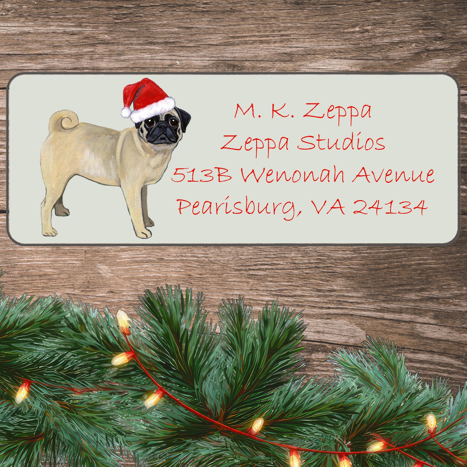 An illustration of a Pug wearing a Santa Hat on an ivory return address label set off by a wood surface with holiday greenery background.