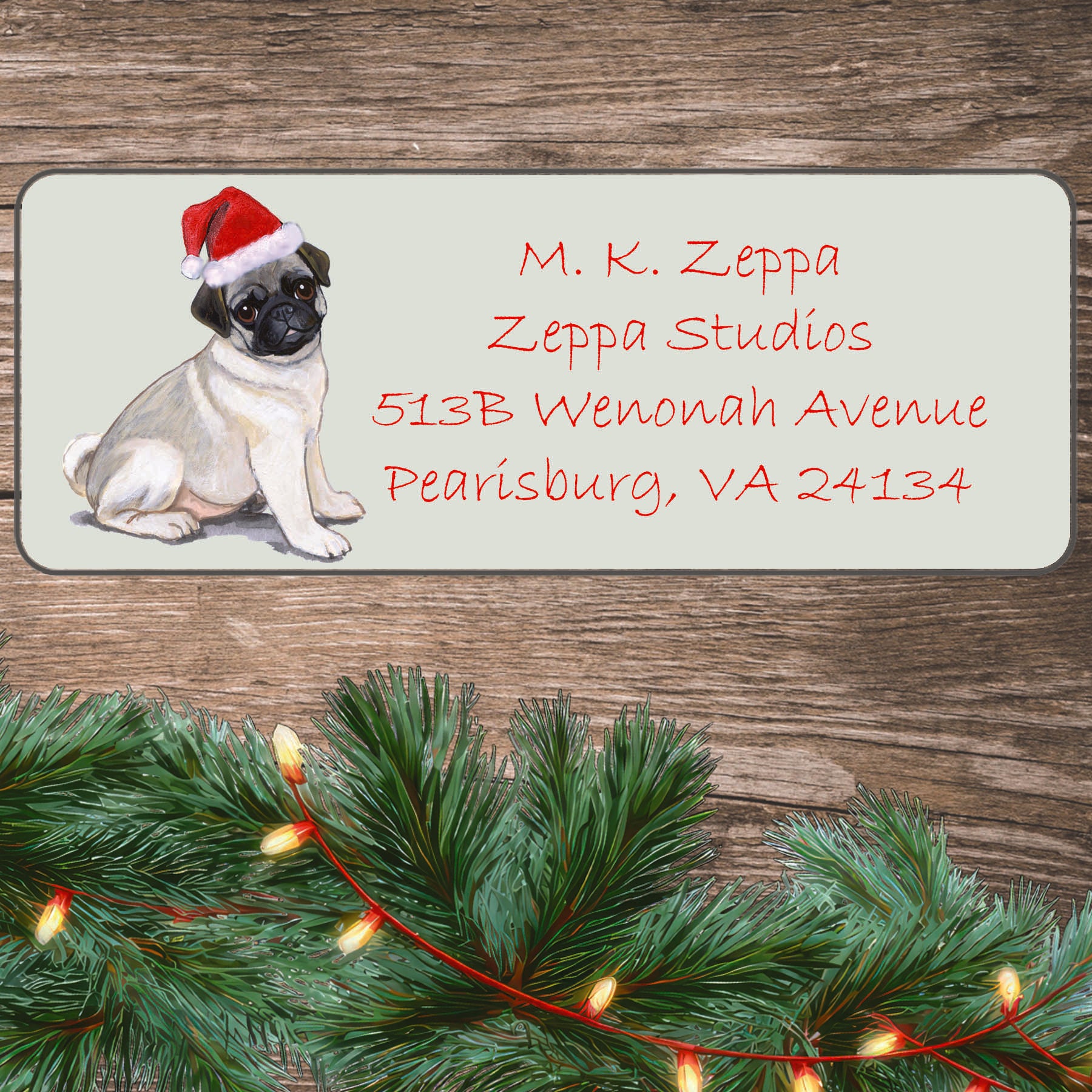 An illustration of a Pug puppy wearing a Santa Hat on an ivory return address label set off by a wood surface with holiday greenery background.