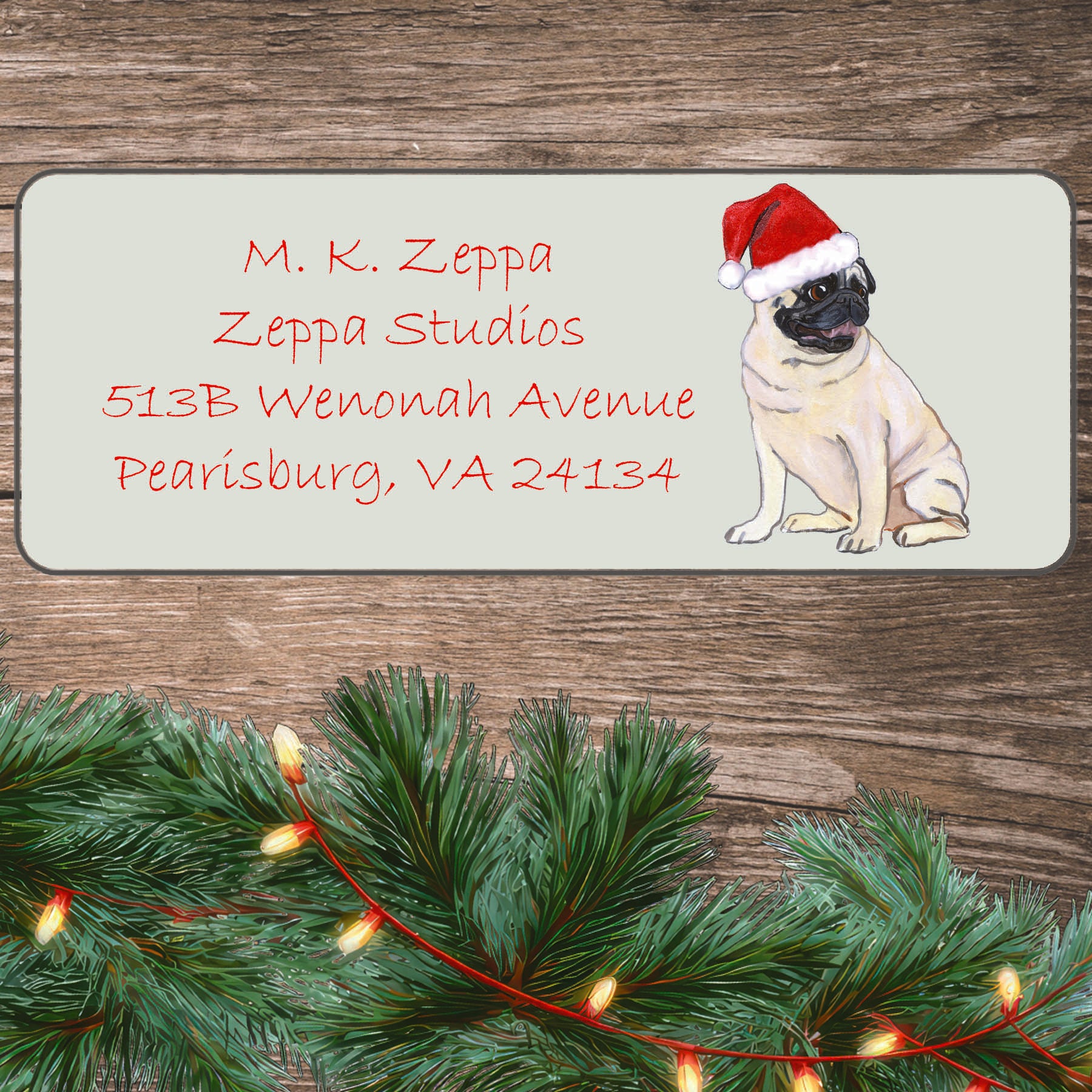 An illustration of a Sitting Pug wearing a Santa Hat on an ivory return address label set off by a wood surface with holiday greenery background.