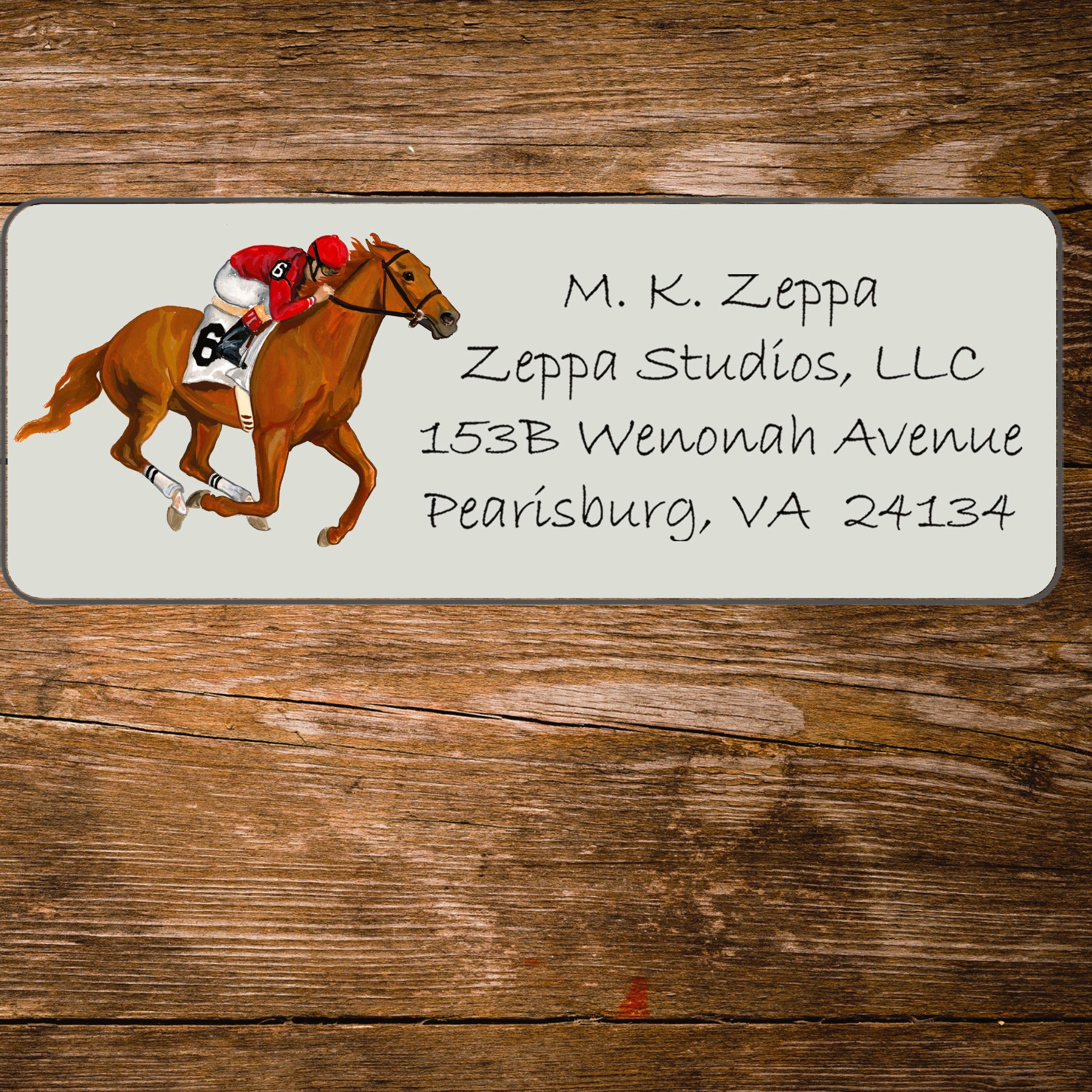 Return address label with horse and jockey illustration on a wooden surface