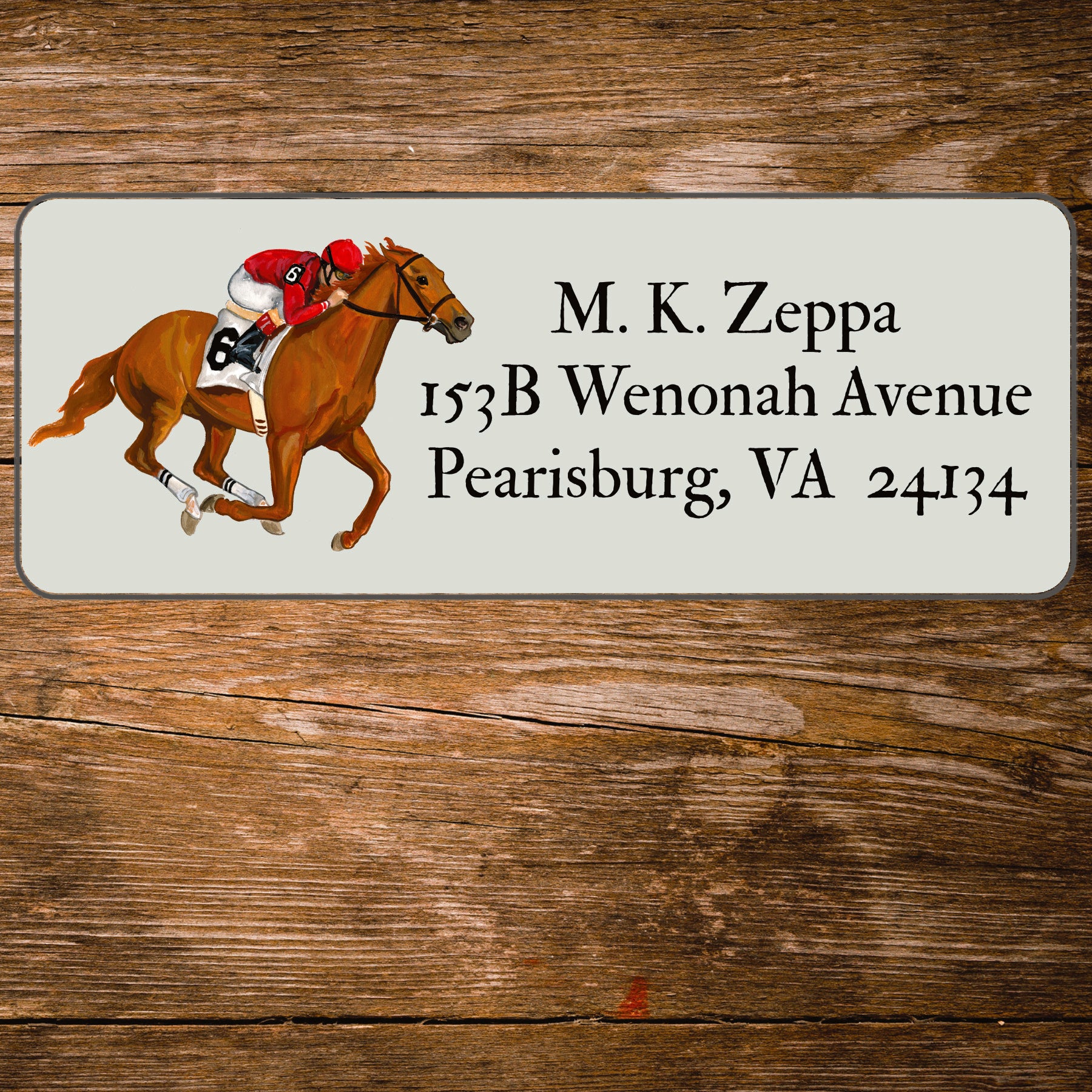 Return address label with horse and jockey illustration on a wooden surface