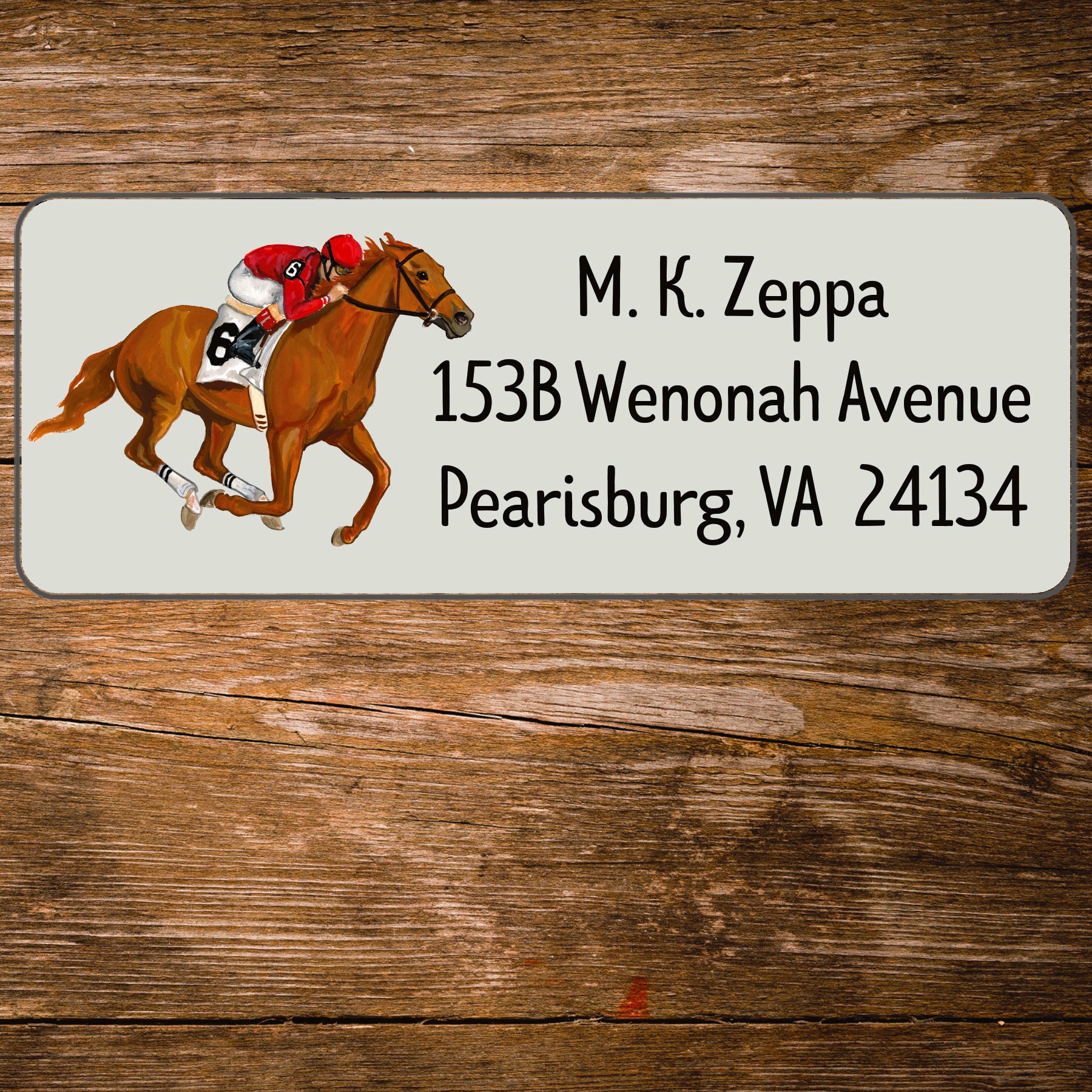 Address label with horse and jockey illustration on a wooden surface