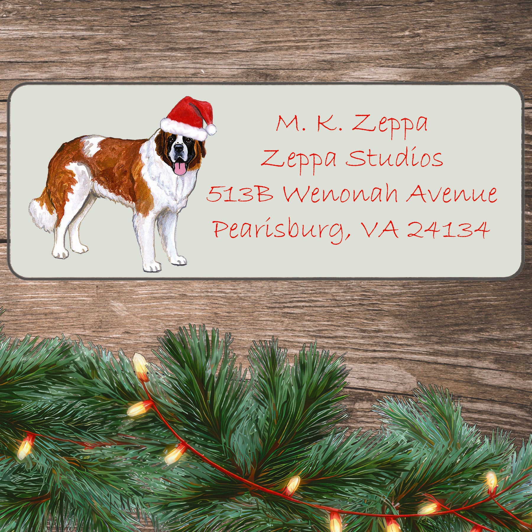 An illustration of a Saint Bernard wearing a Santa Hat on an ivory return address label set off by a wood surface with holiday greenery background.