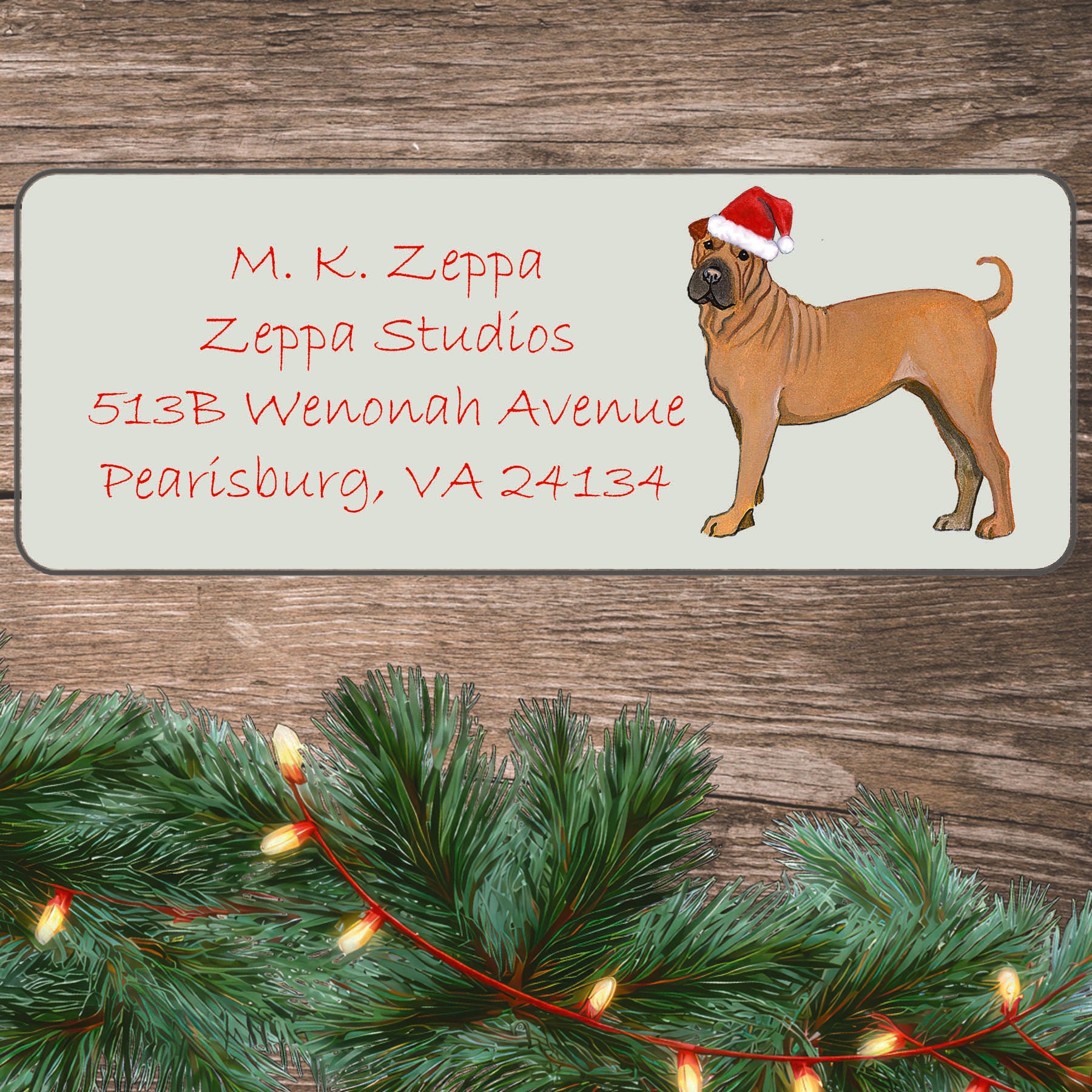 An illustration of a Shar Pei wearing a Santa Hat on an ivory return address label set off by a wood surface with holiday greenery background.