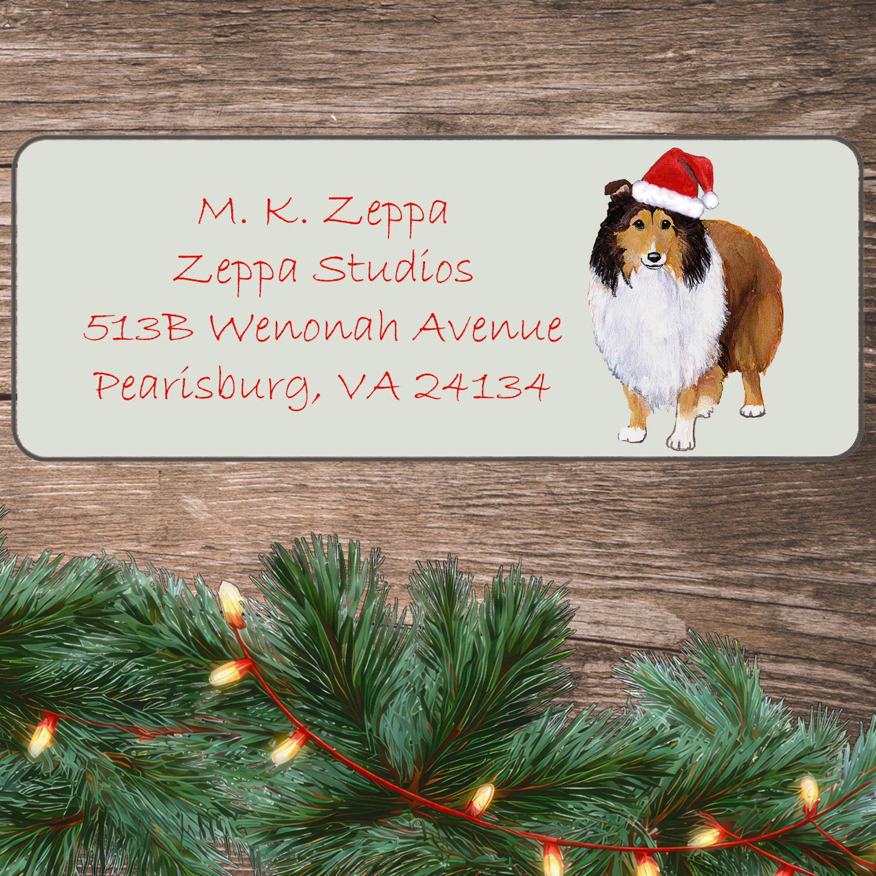 An illustration of a Shetland Sheepdog wearing a Santa Hat on an ivory return address label set off by a wood surface with holiday greenery background.