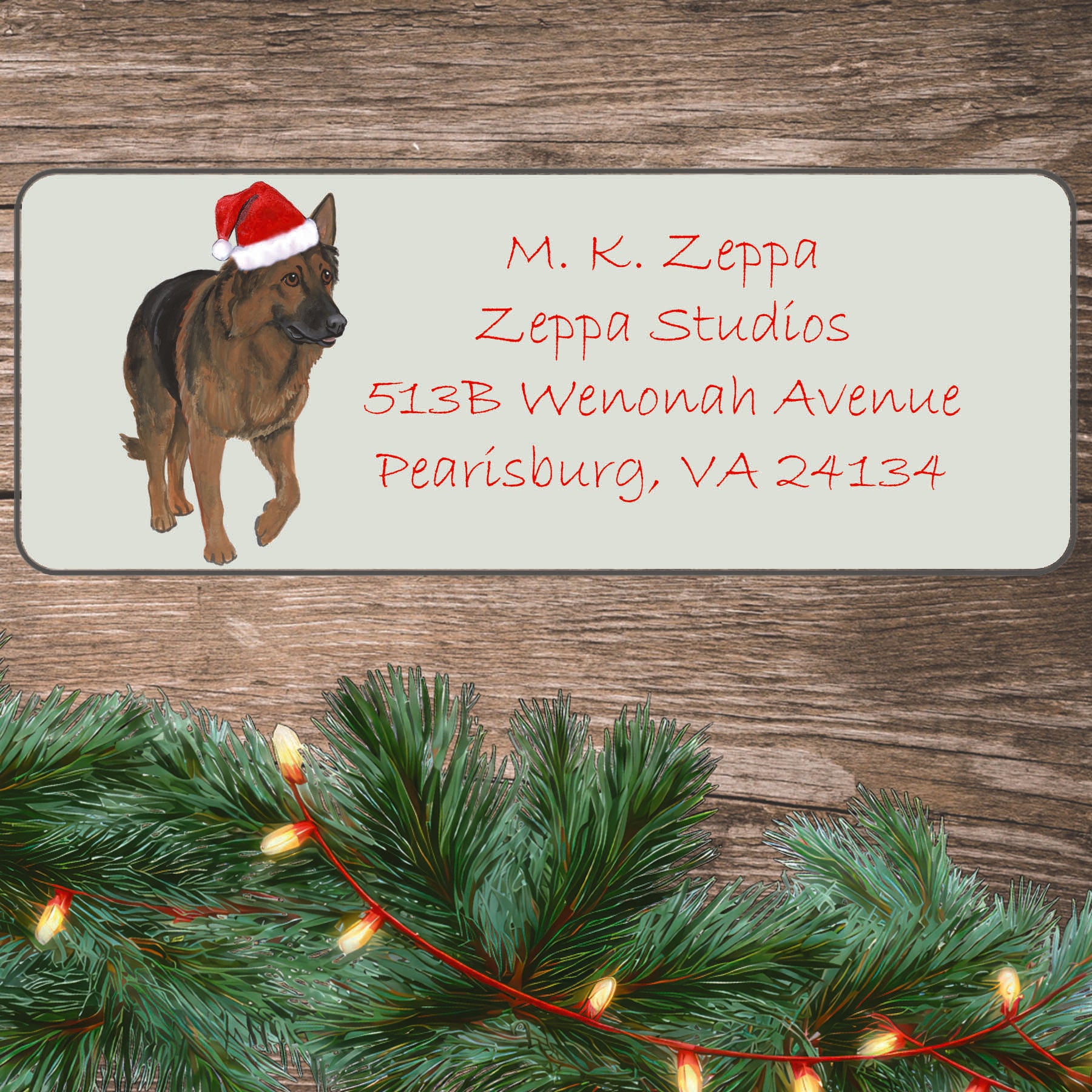 An illustration of a Shiloh Shepherd wearing a Santa Hat on an ivory return address label set off by a wood surface with holiday greenery background.