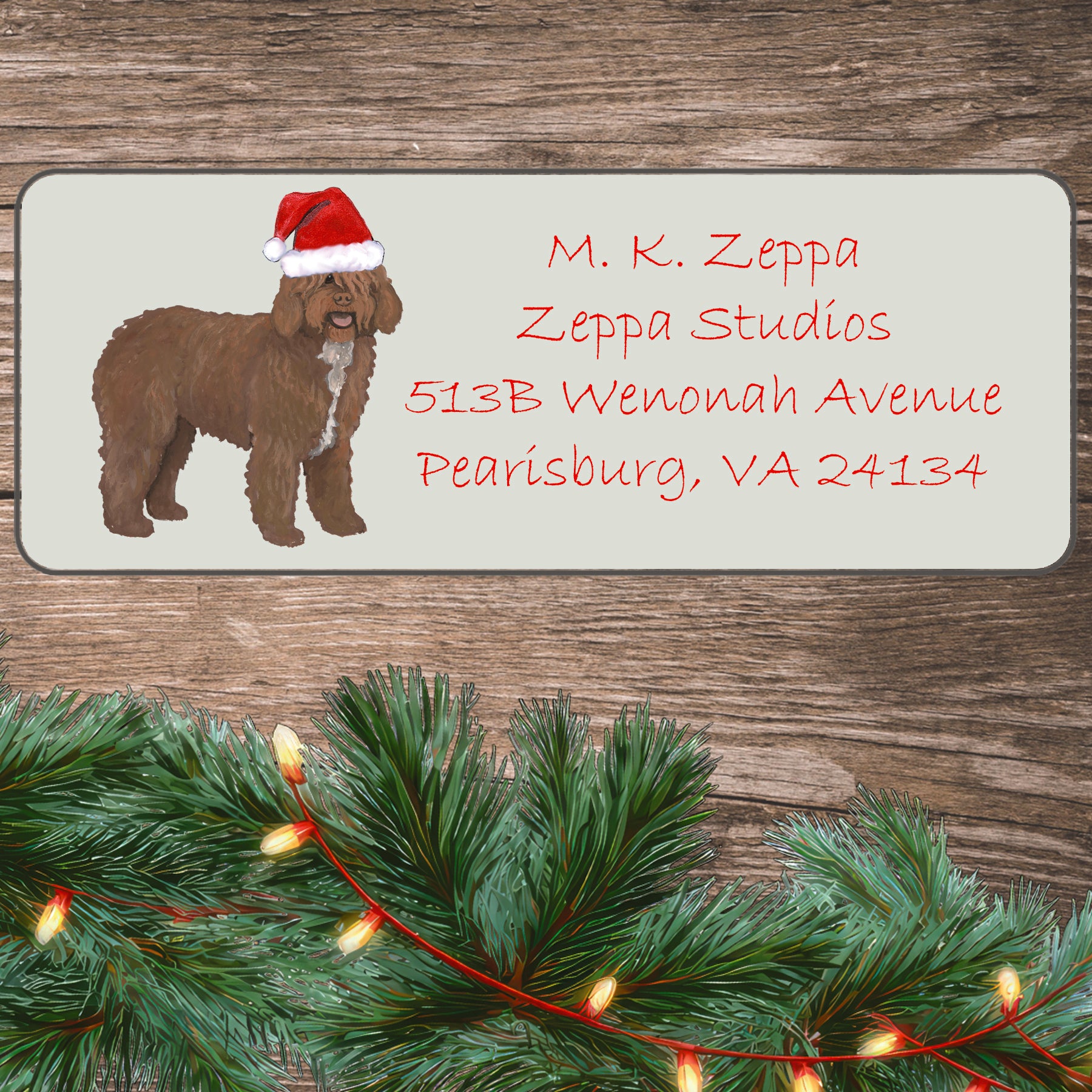 An illustration of a Spanish Water Dog wearing a Santa Hat on an ivory return address label set off by a wood surface with holiday greenery background.