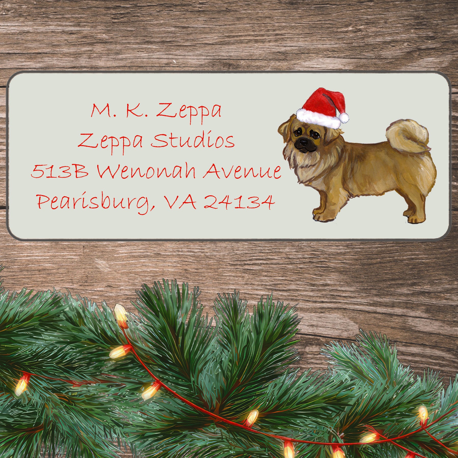 An illustration of a Tibetan Spaniel wearing a Santa Hat on an ivory return address label set off by a wood surface with holiday greenery background.