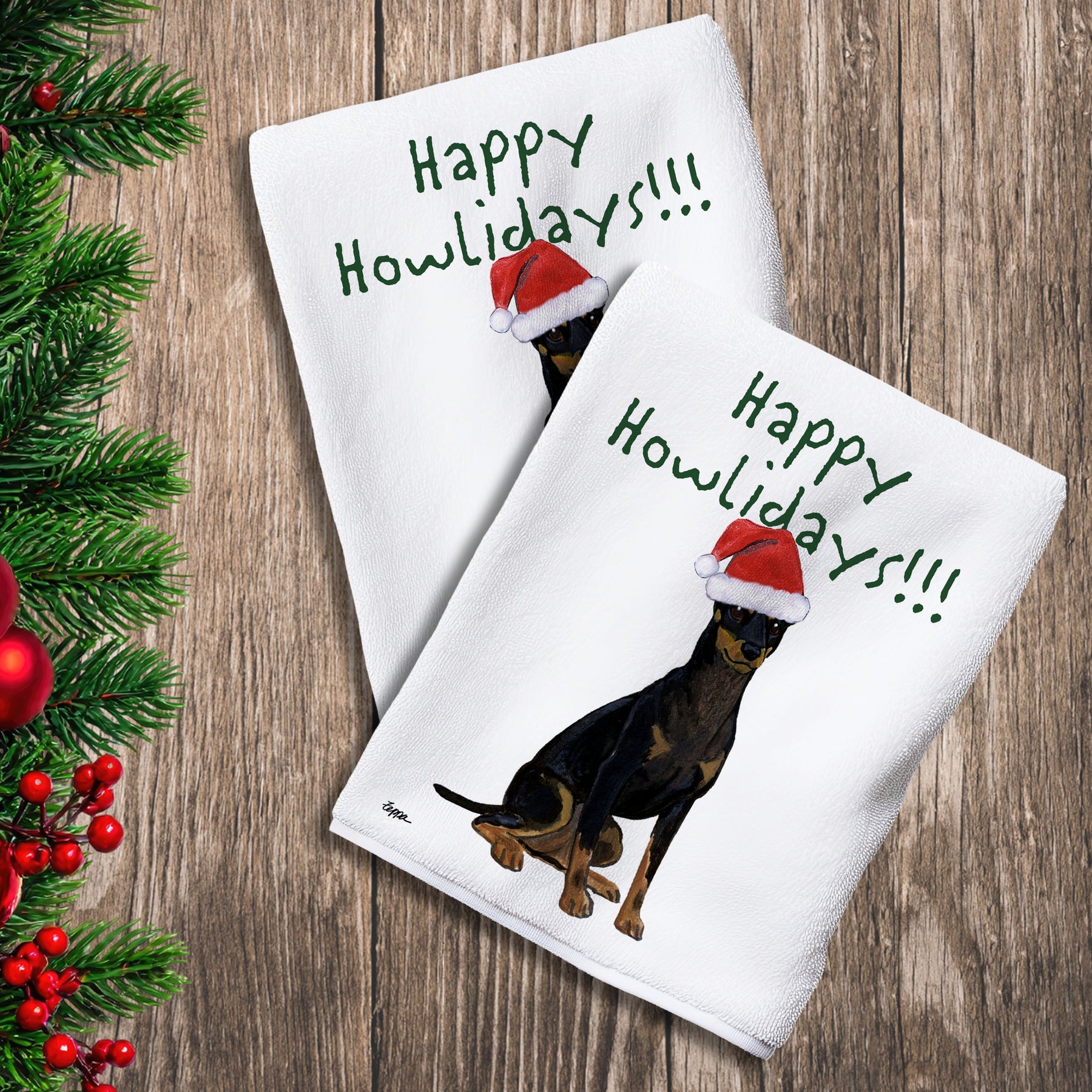 2 Kitchen Towels with a Toy Manchester Terrier in a Santa Hat and Happy Howlidays text.