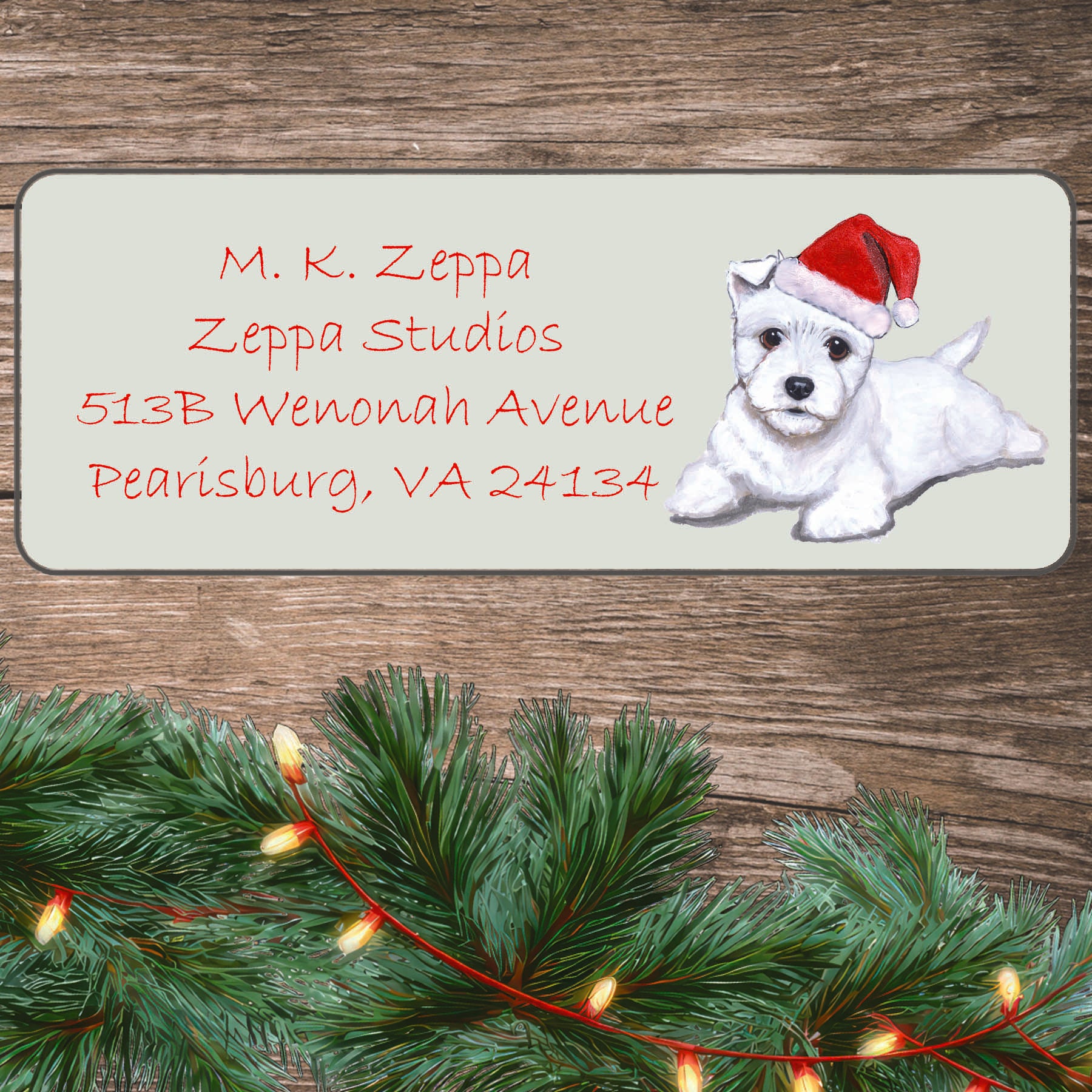 An illustration of a West Highland White  Terrier Puppy wearing a Santa Hat on an ivory return address label set off by a wood surface with holiday greenery background.