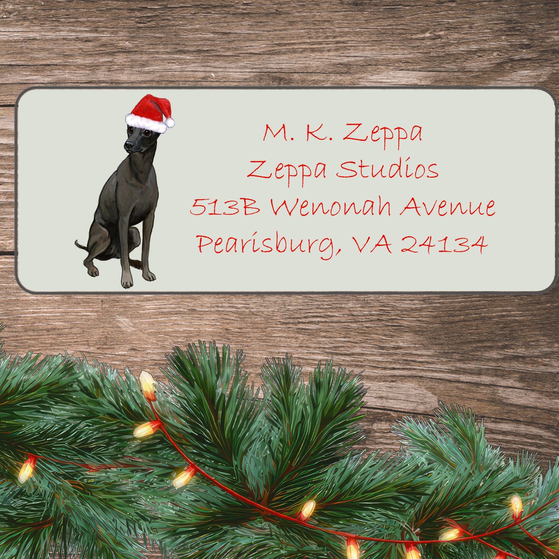 An illustration of a Xoloitzcuintli wearing a Santa Hat on an ivory return address label set off by a wood surface with holiday greenery background.
