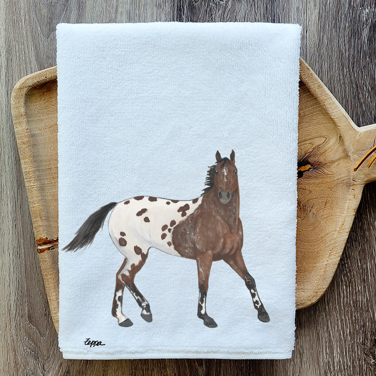 Appaloosa kitchen towel on a wooden cutting board.