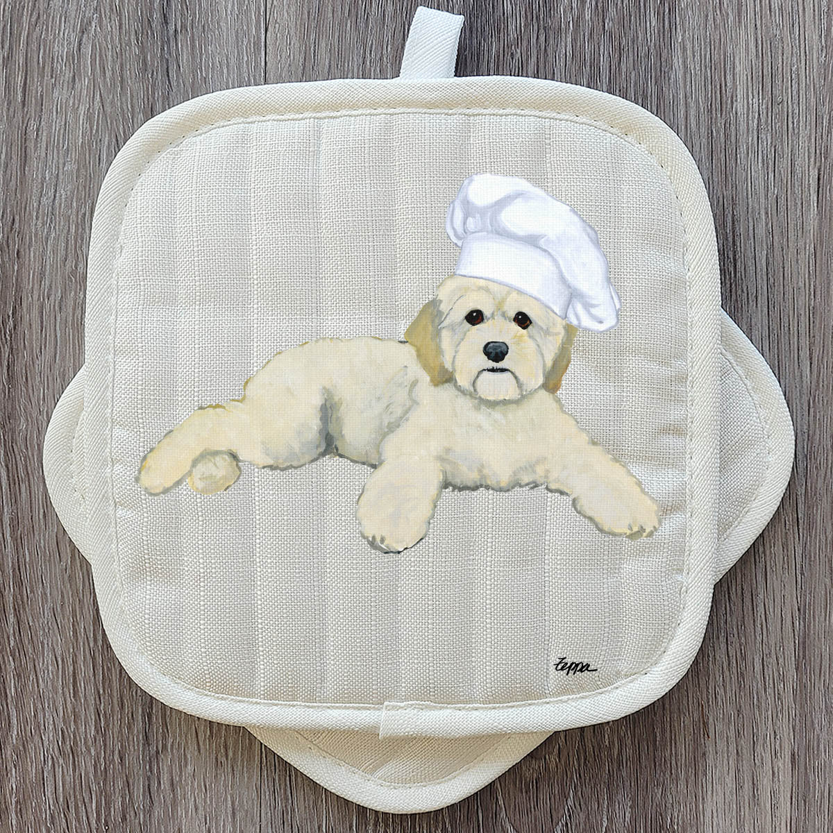 Cockapoo in a chef's hat on a pair of pot holders.